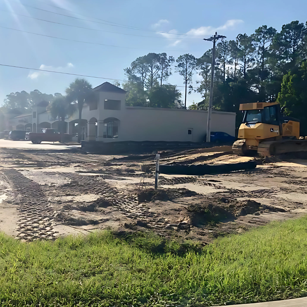Construction site with a bulldozer, building, and mud.