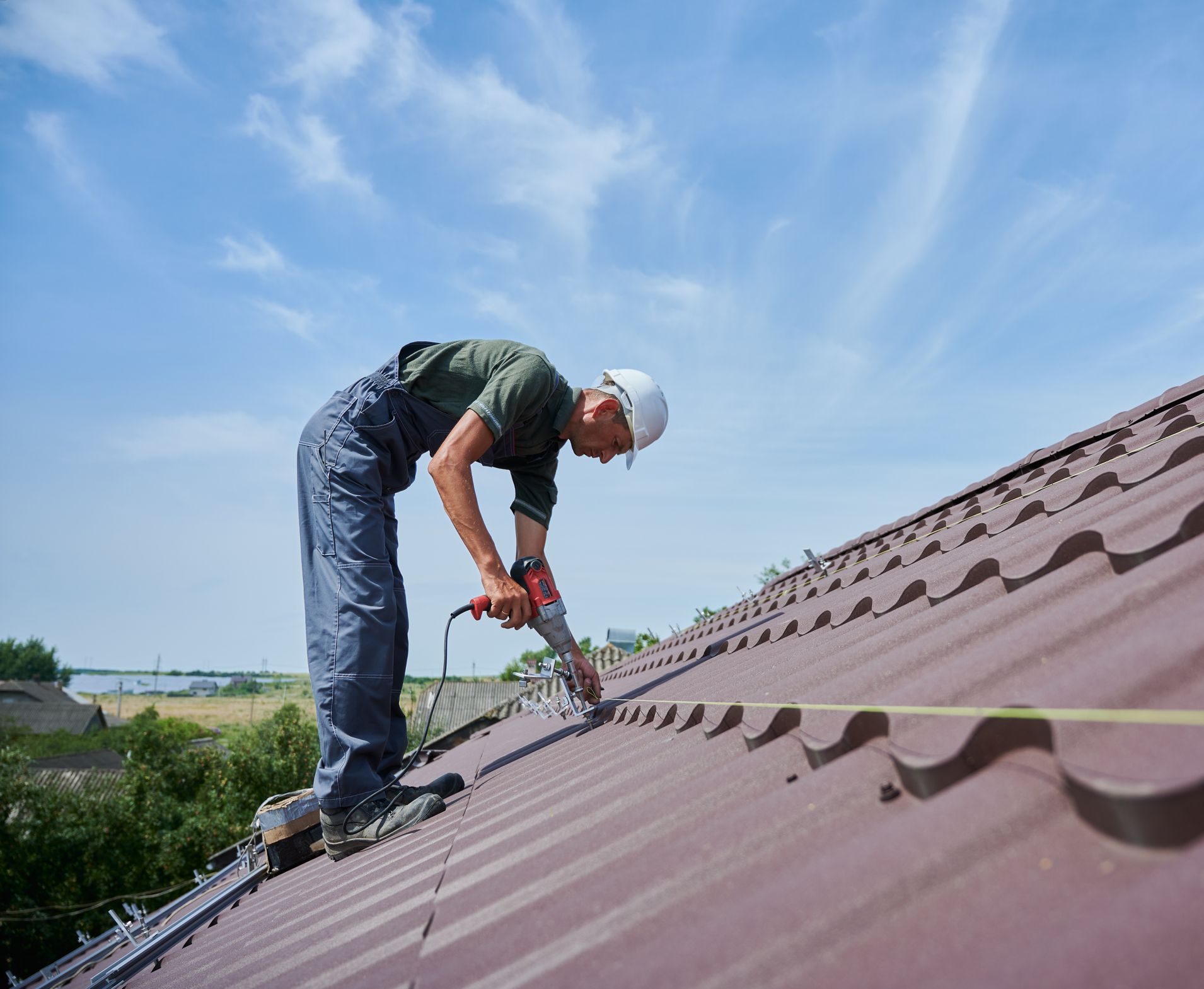 A man is working on a roof with a drill.