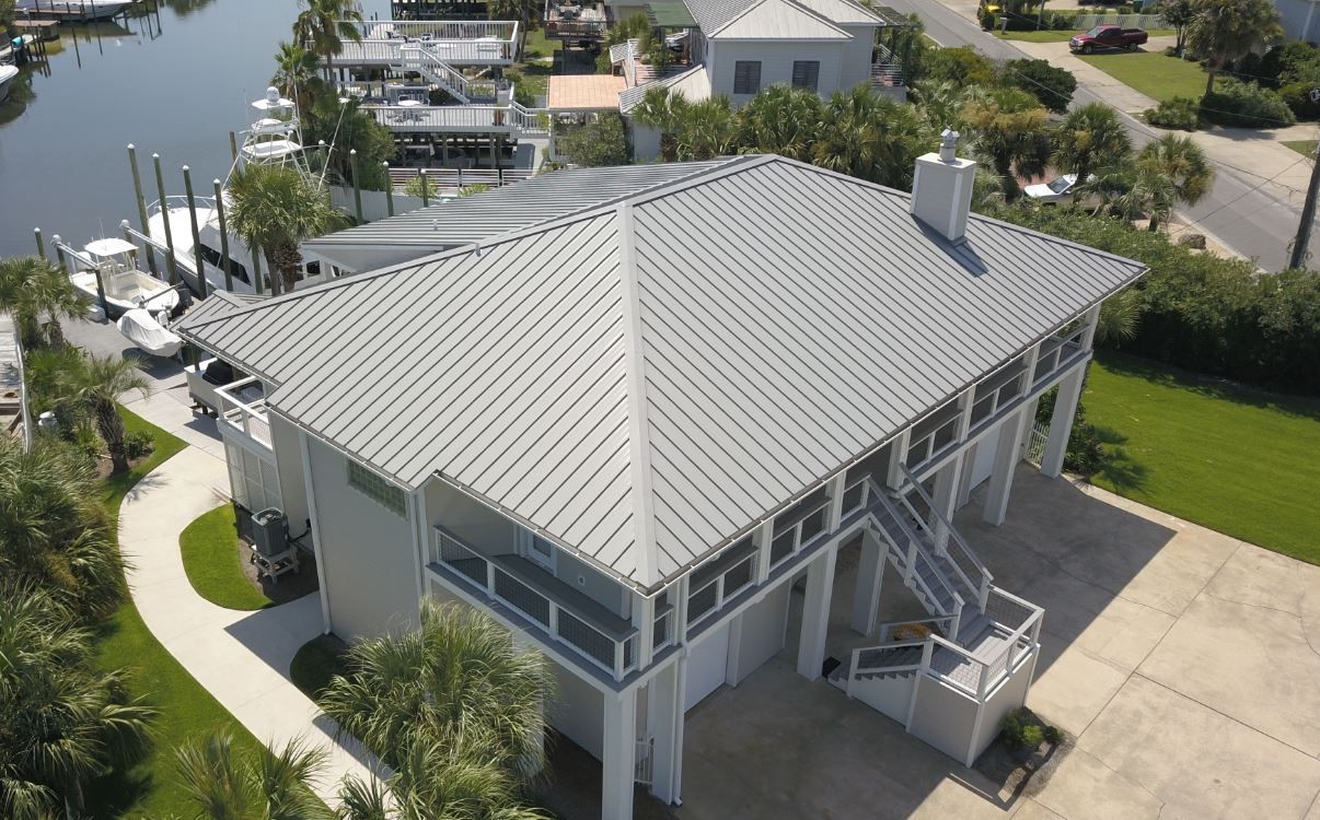 An aerial view of a large white house next to a body of water.