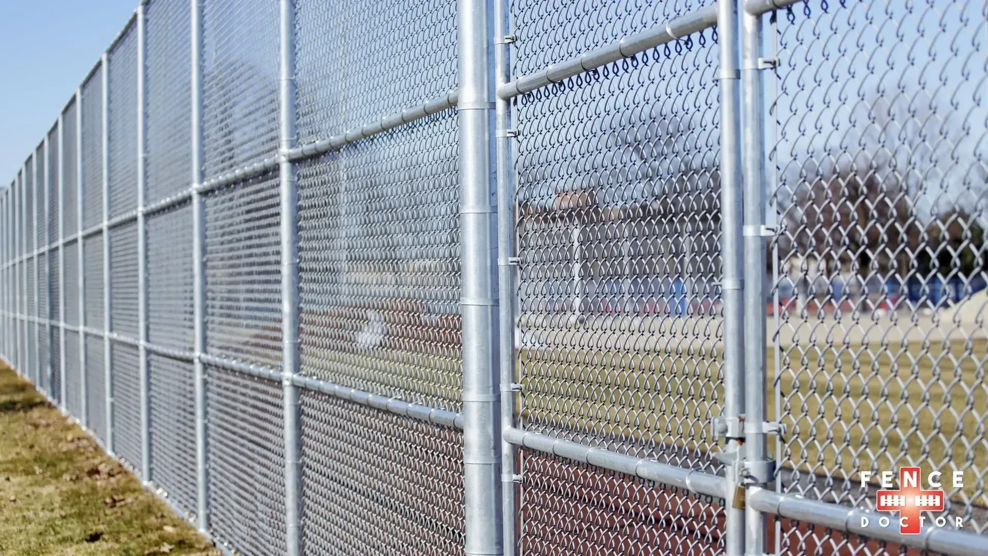 A metal gate in Columbus ga is surrounded by stone pillars on the side of a gravel road.