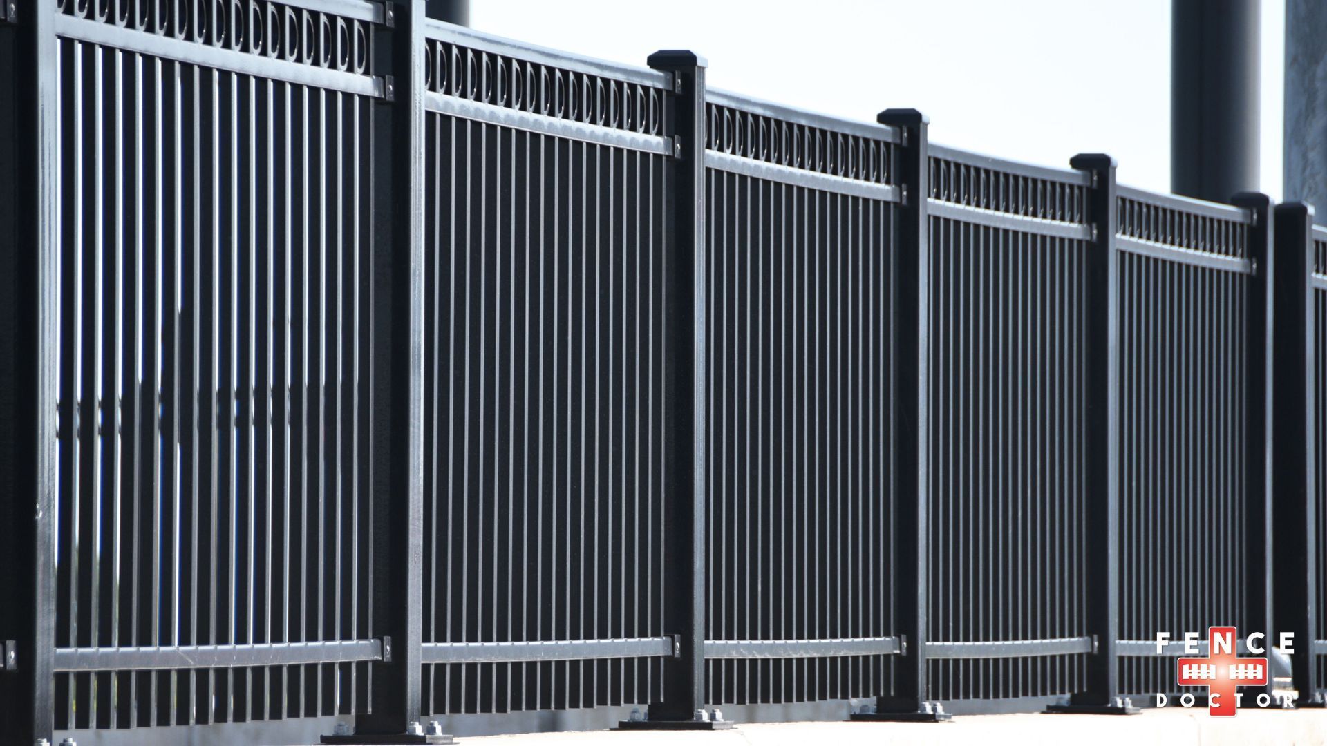 A metal gate in Columbus Ga is surrounded by stone pillars on the side of a gravel road.