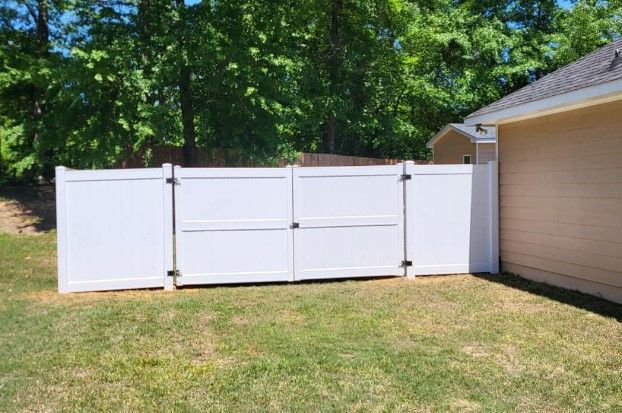 A white fence is in the backyard of a house in LaGrange Ga