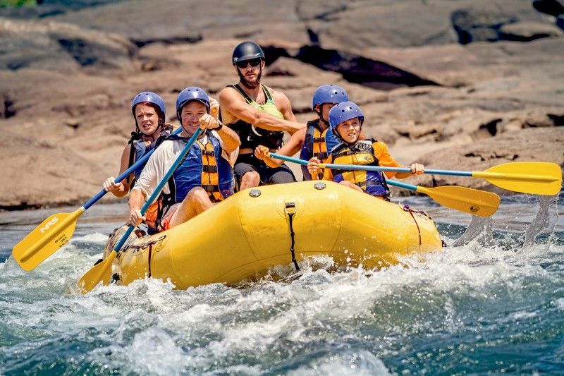 A group of people are rafting down a river in a yellow raft in Columbus Ga.