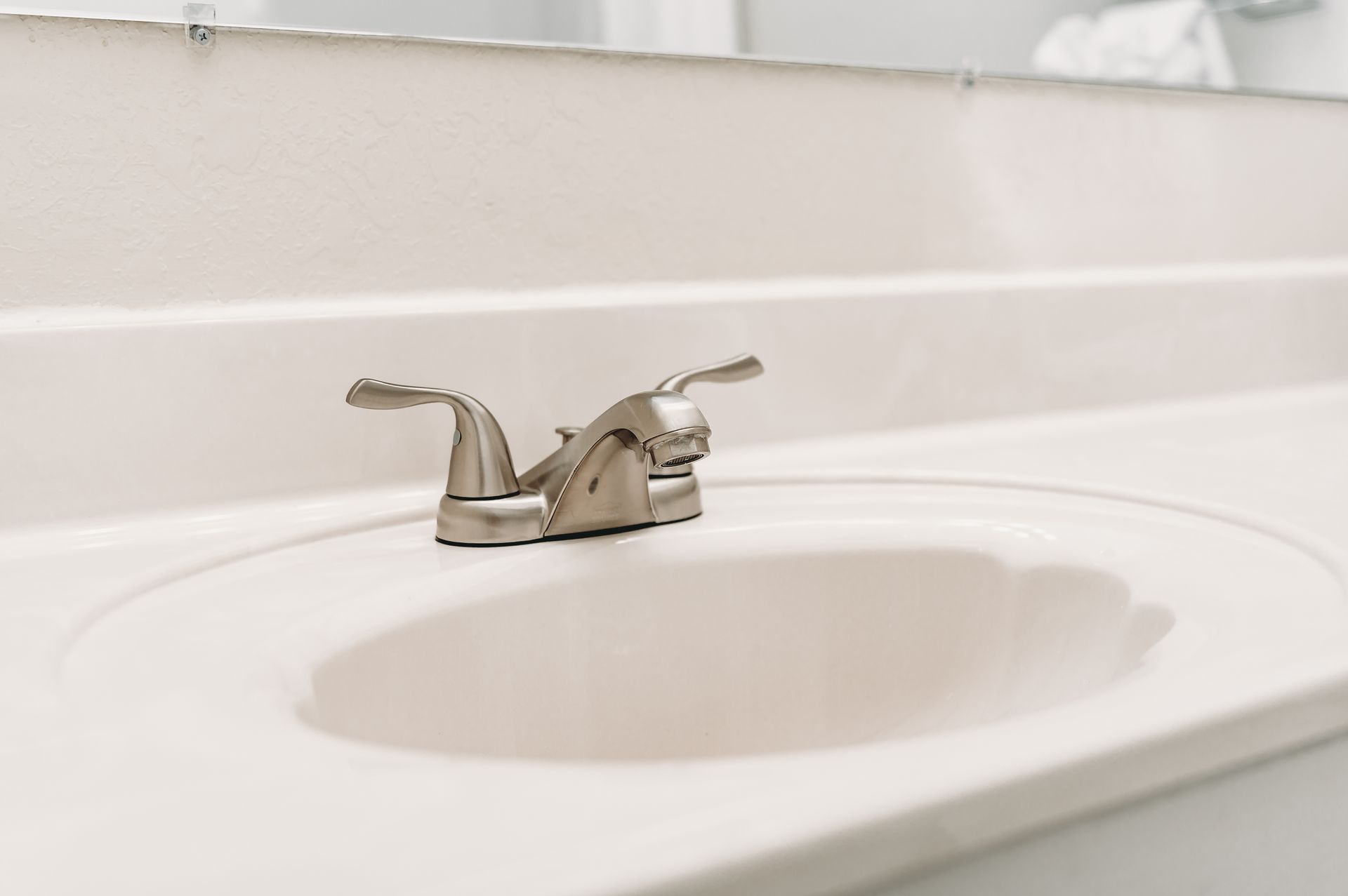 A white bathroom sink with a silver faucet is centered on the countertop.
