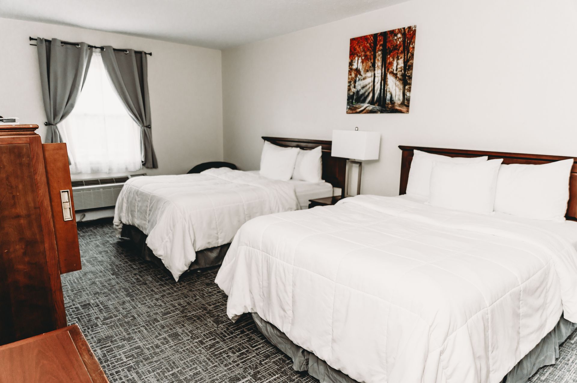 Bedroom with two beds, white bedding, gray curtains, and a colorful painting.