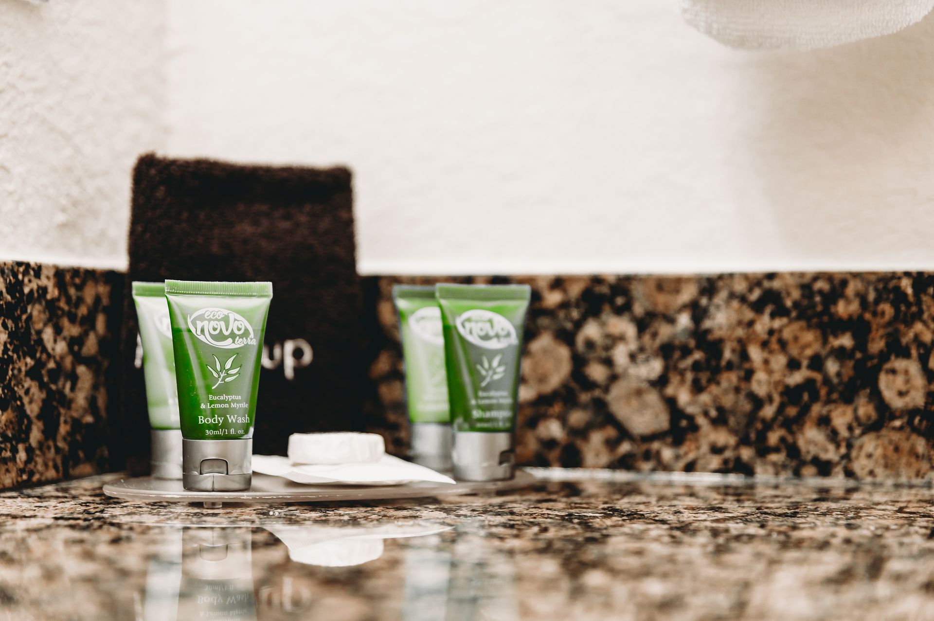 Bathroom toiletries: green tubes, dark towel, white washcloths on a granite countertop.