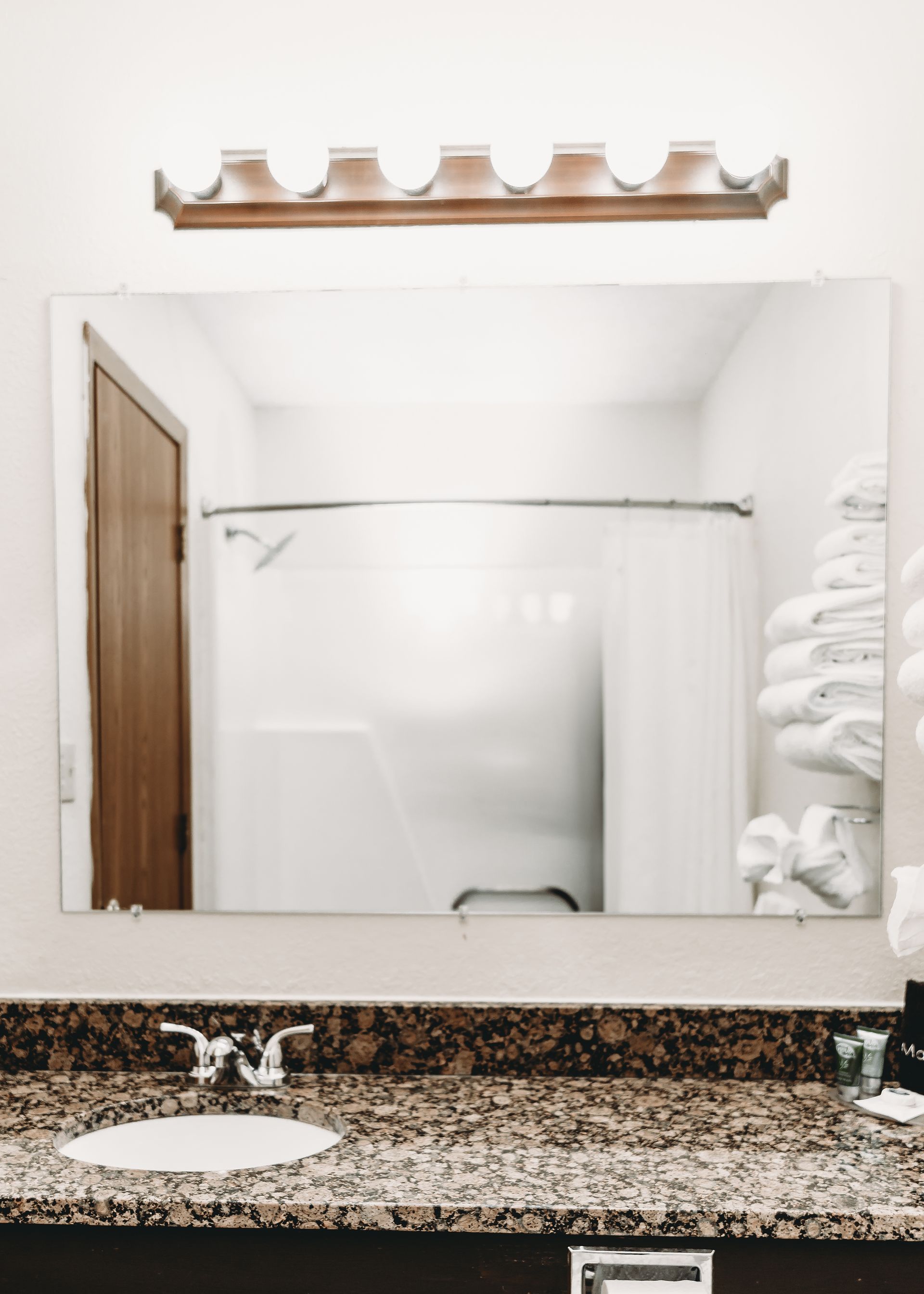 Bathroom with mirror, sink, and towels. Shower visible in reflection.