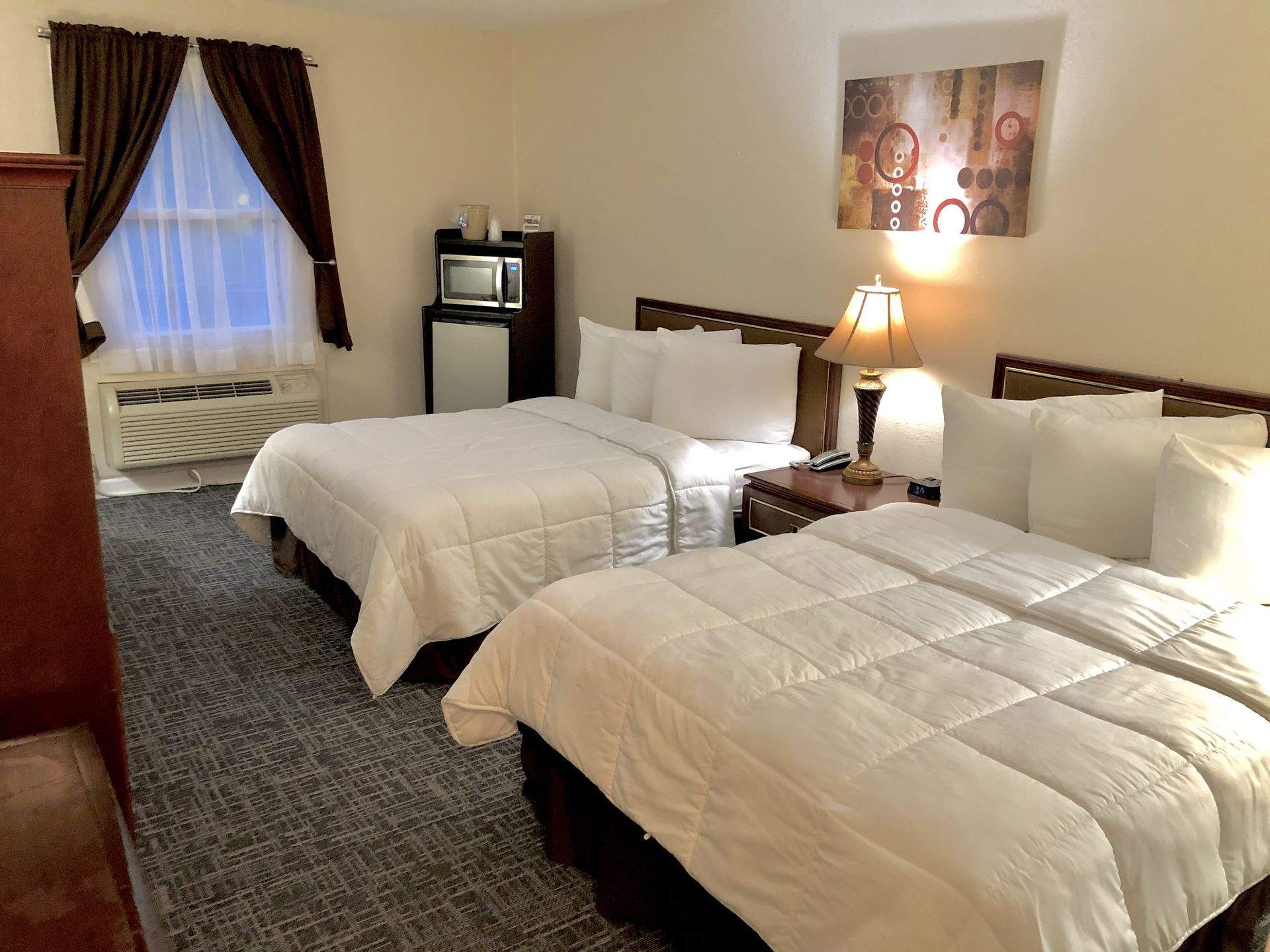 Hotel room with two beds, a desk, and a wardrobe with a TV.