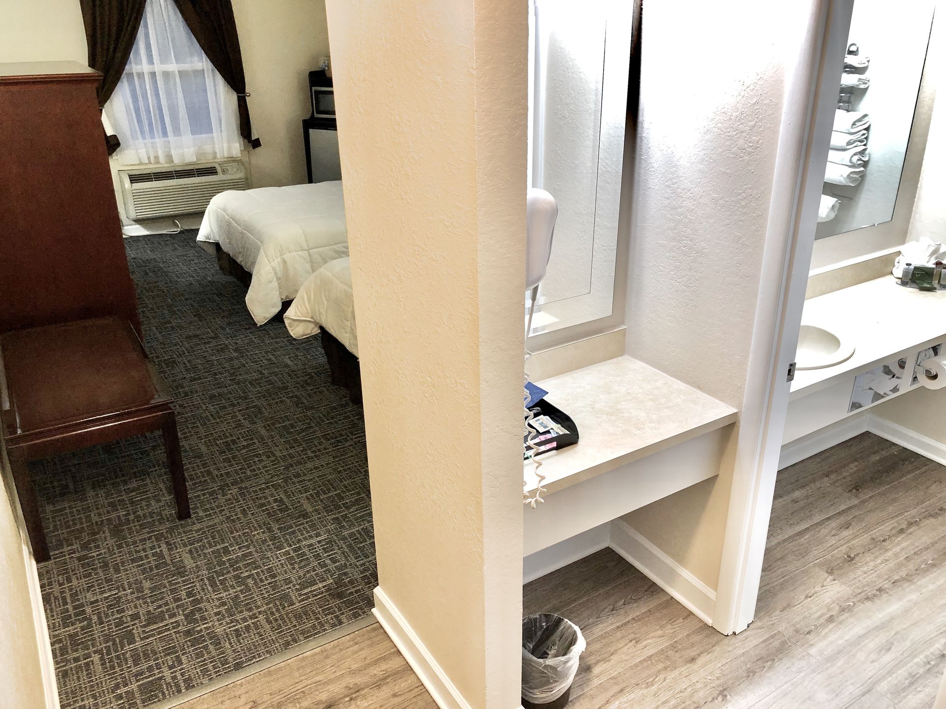 Hotel room with a bed, bathroom, chair, and window with curtains.