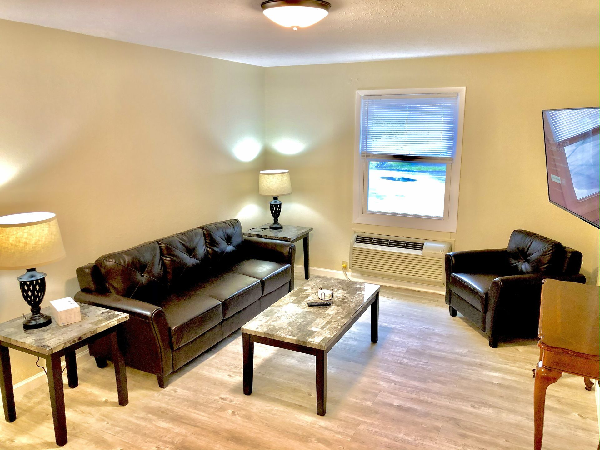 Cozy living room with brown sofa, armchair, coffee table, window, TV, and lamps.