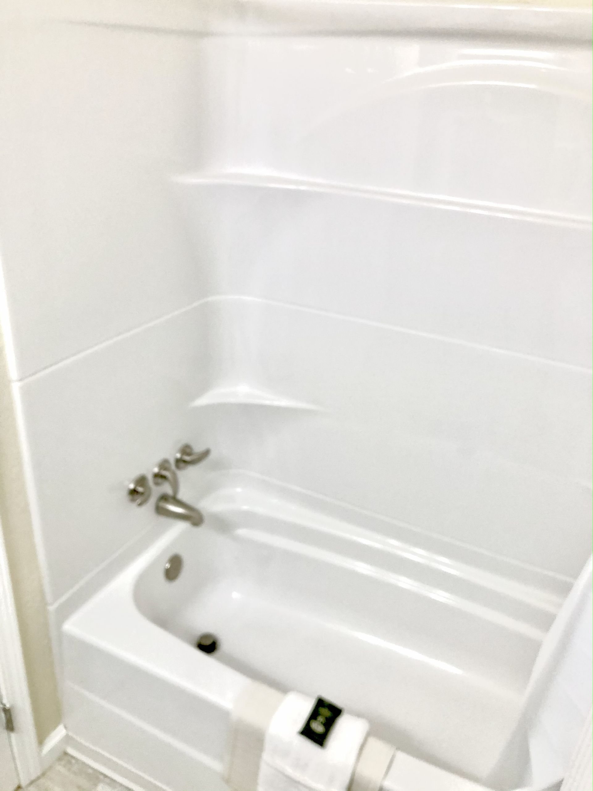 White bathtub and shower combo with shelves and chrome faucet.