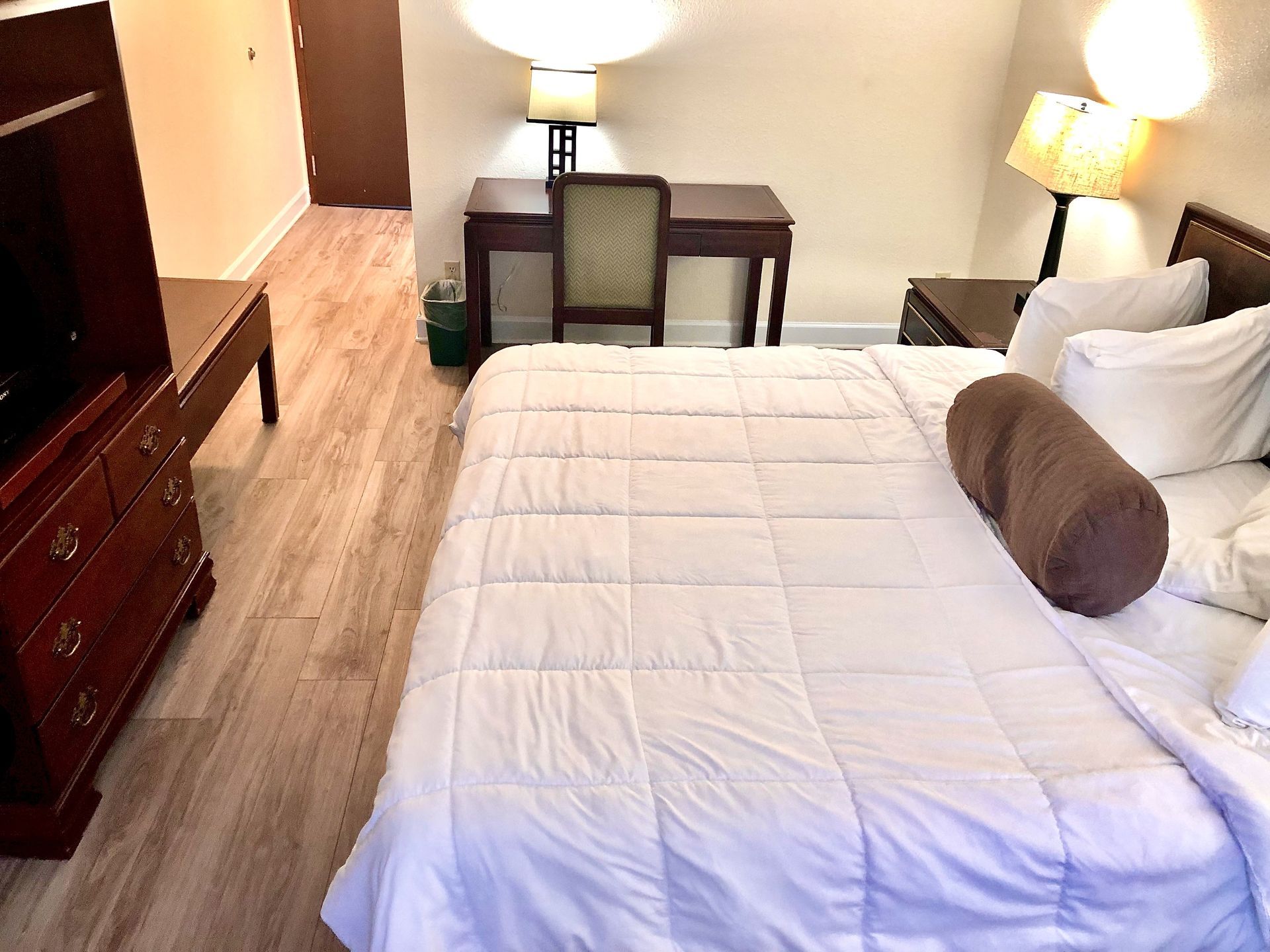 Bedroom with bed, desk, dresser, and lamps.