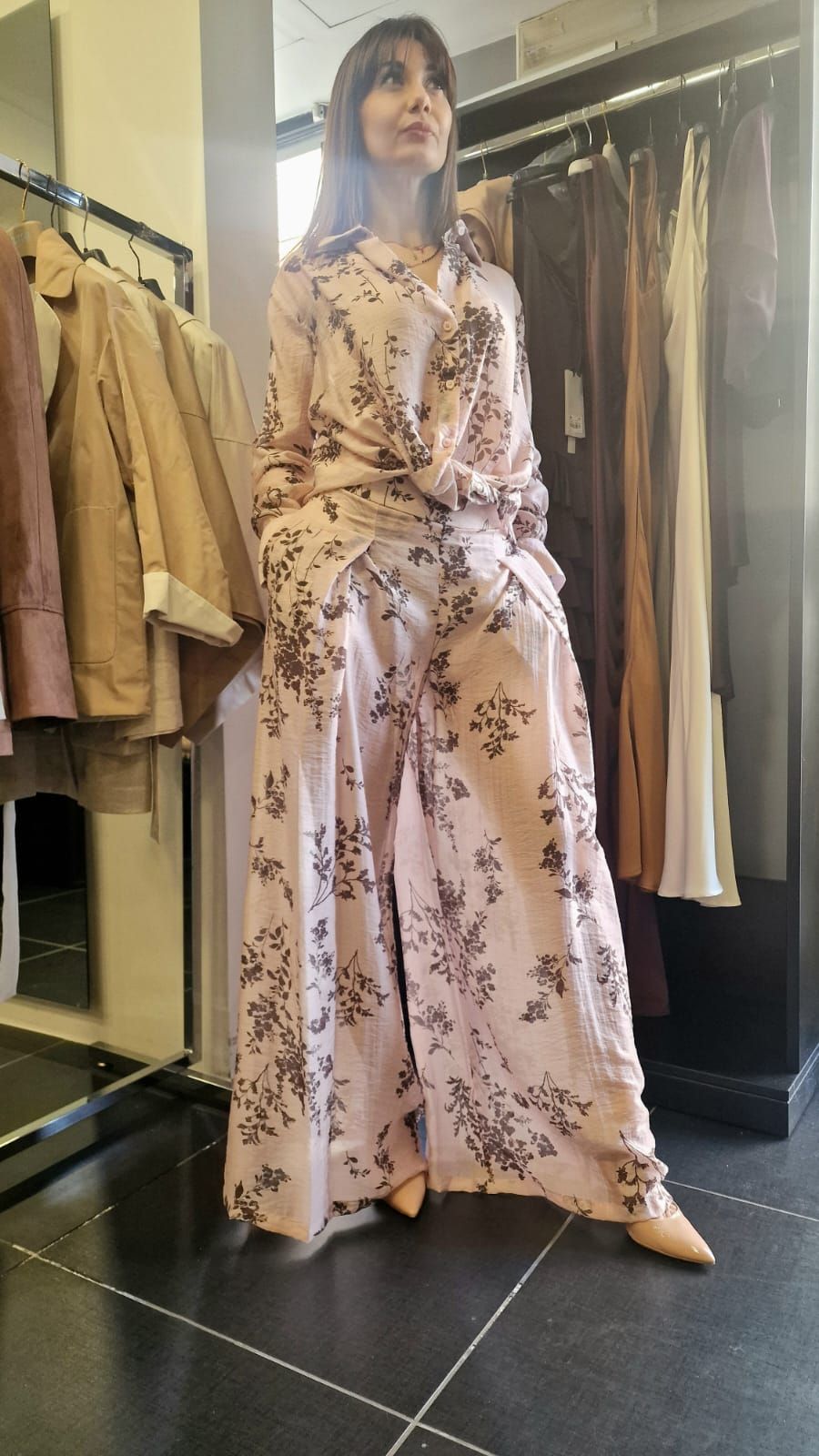 Una persona che indossa un abito rosa a fiori si trova in un camerino di prova in un negozio di abbigliamento.
