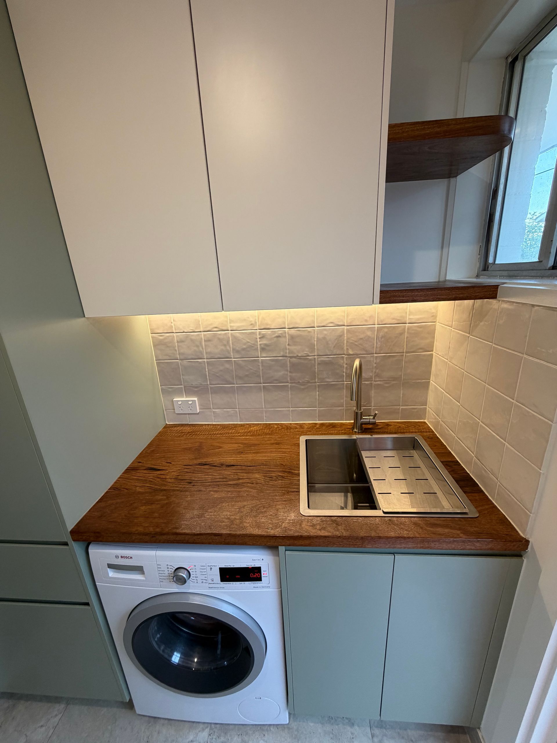 Laundry room with a washing machine, sink, and cabinets; sage green and white colour scheme. — Straight up Building Projects in Holt, ACT