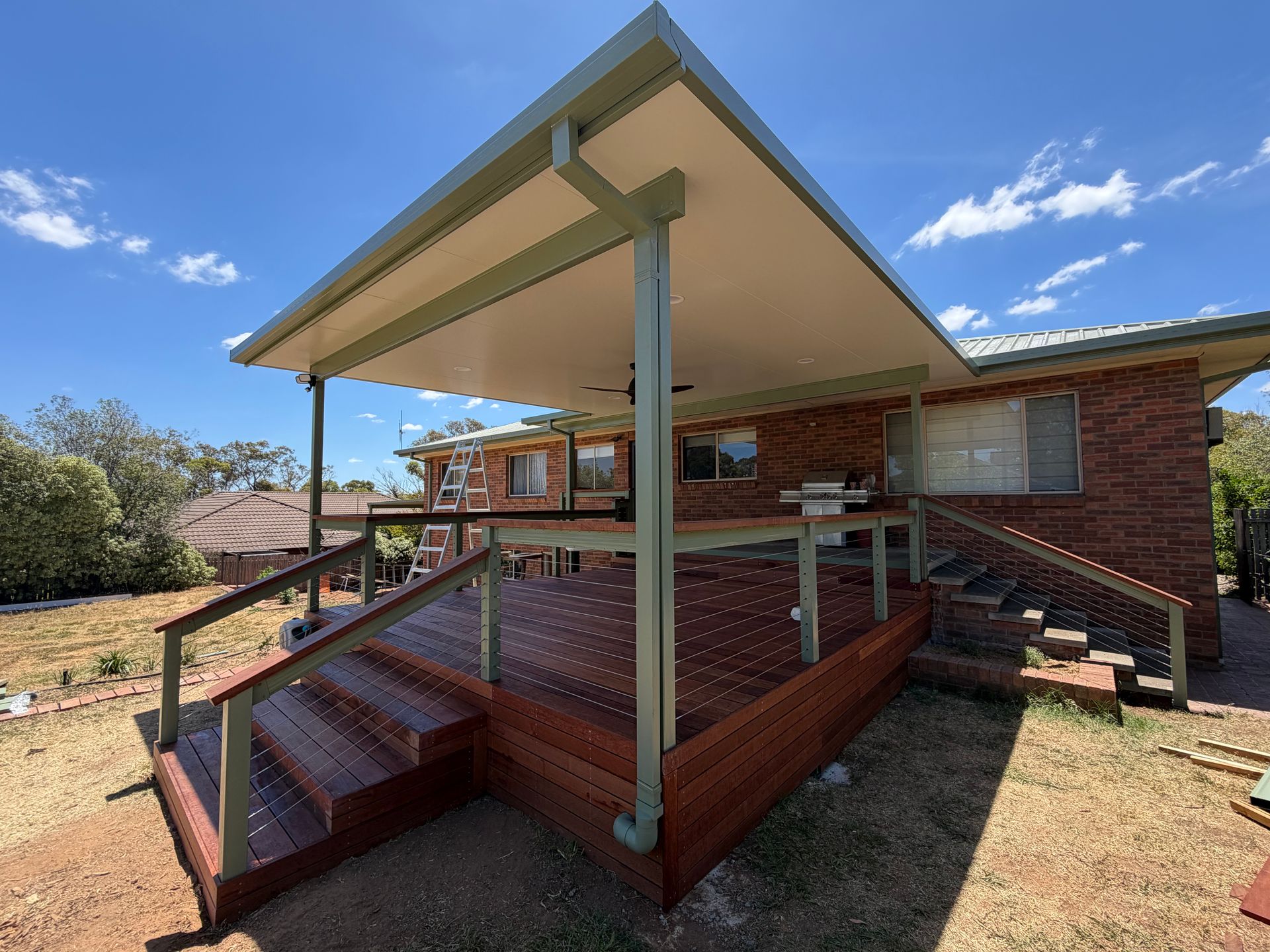 A large, covered wooden deck attached to a brick house under a bright blue sky — Straight up Building Projects in Weston Creek, ACT