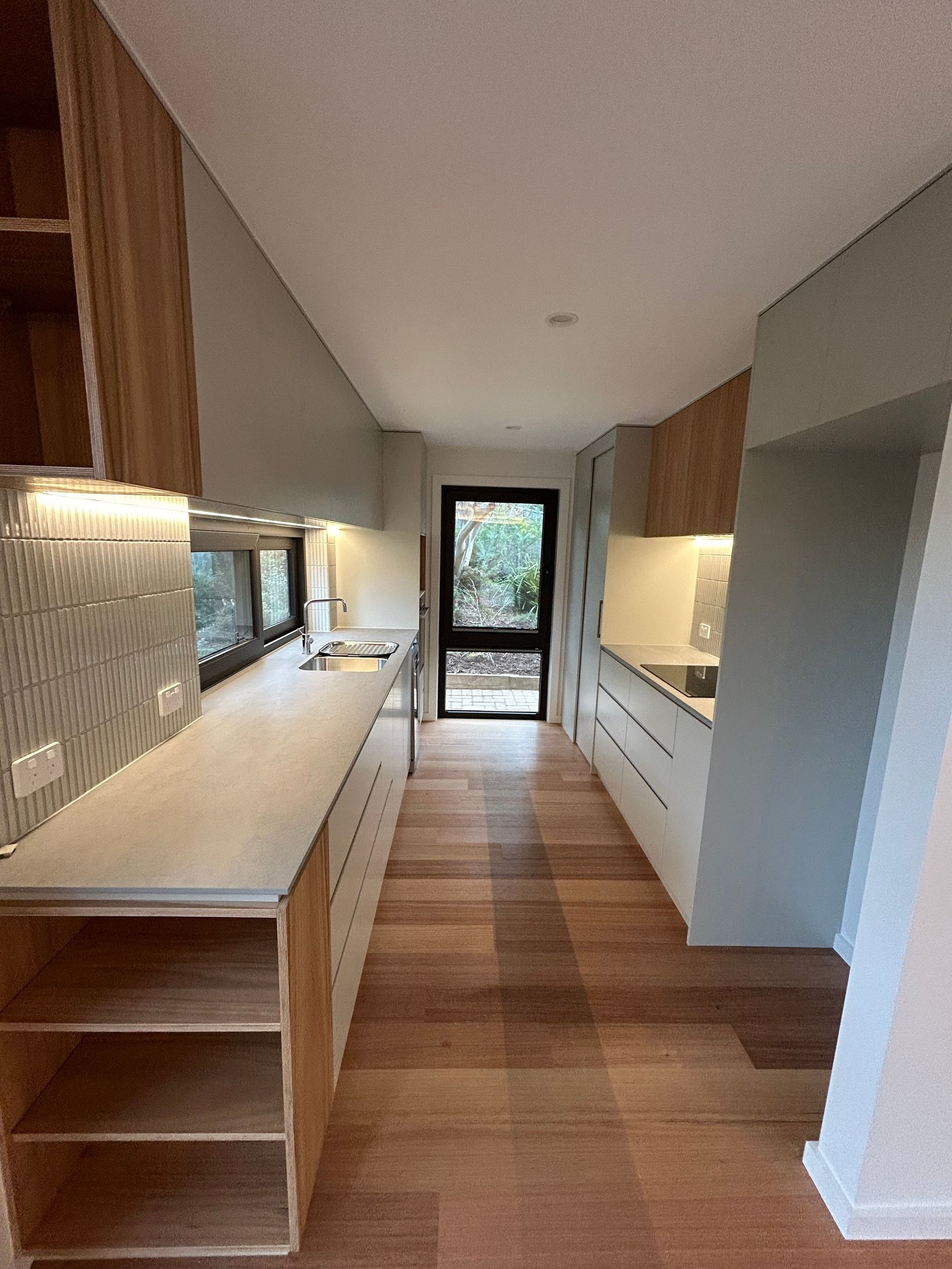 Modern kitchen with light wood cabinetry, white countertops, and wood flooring. — Straight up Building Projects in Holt, ACT