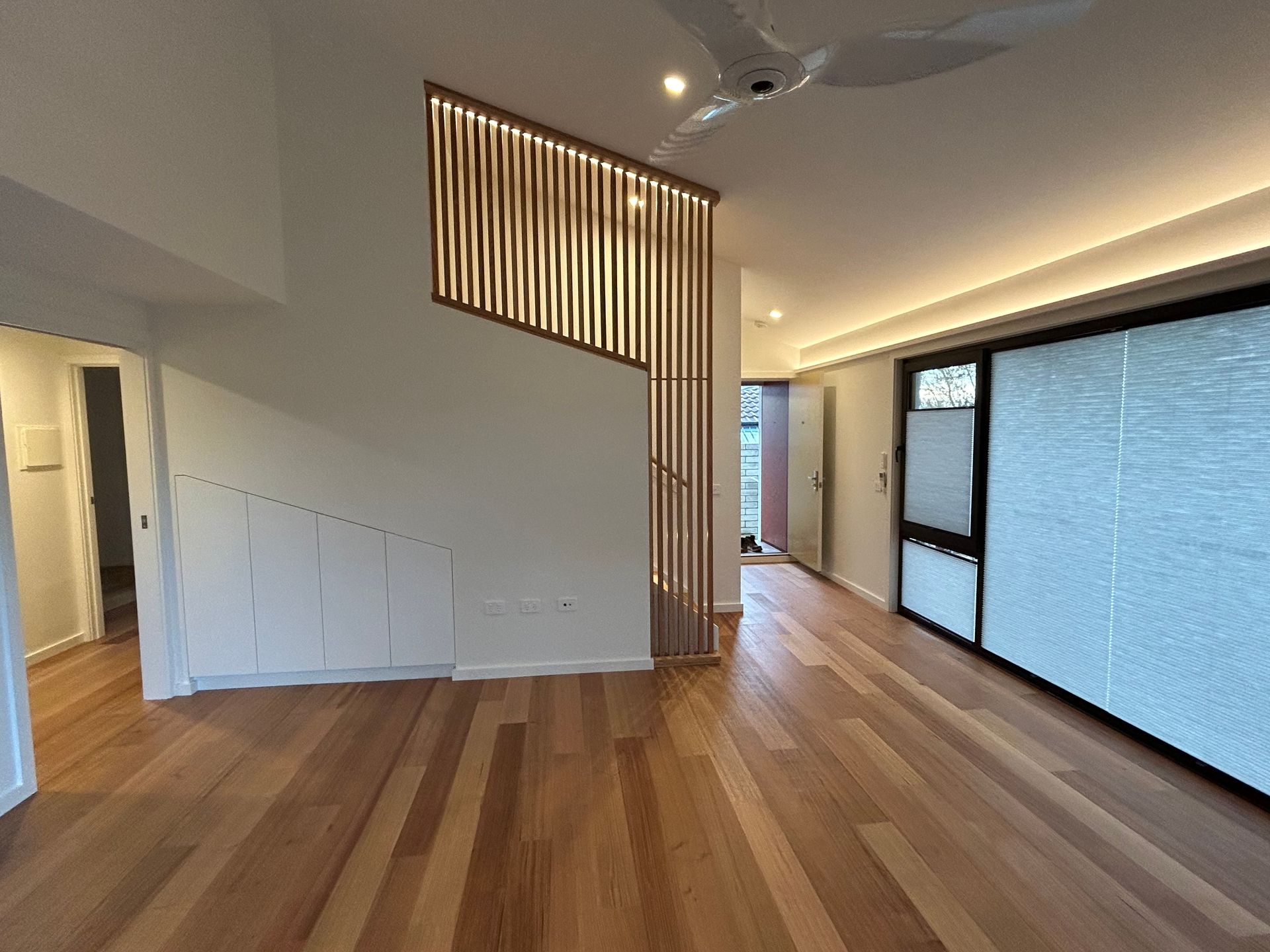 Wooden floor interior with slatted wood design wall feature and sliding glass doors. — Straight up Building Projects in Holt, ACT