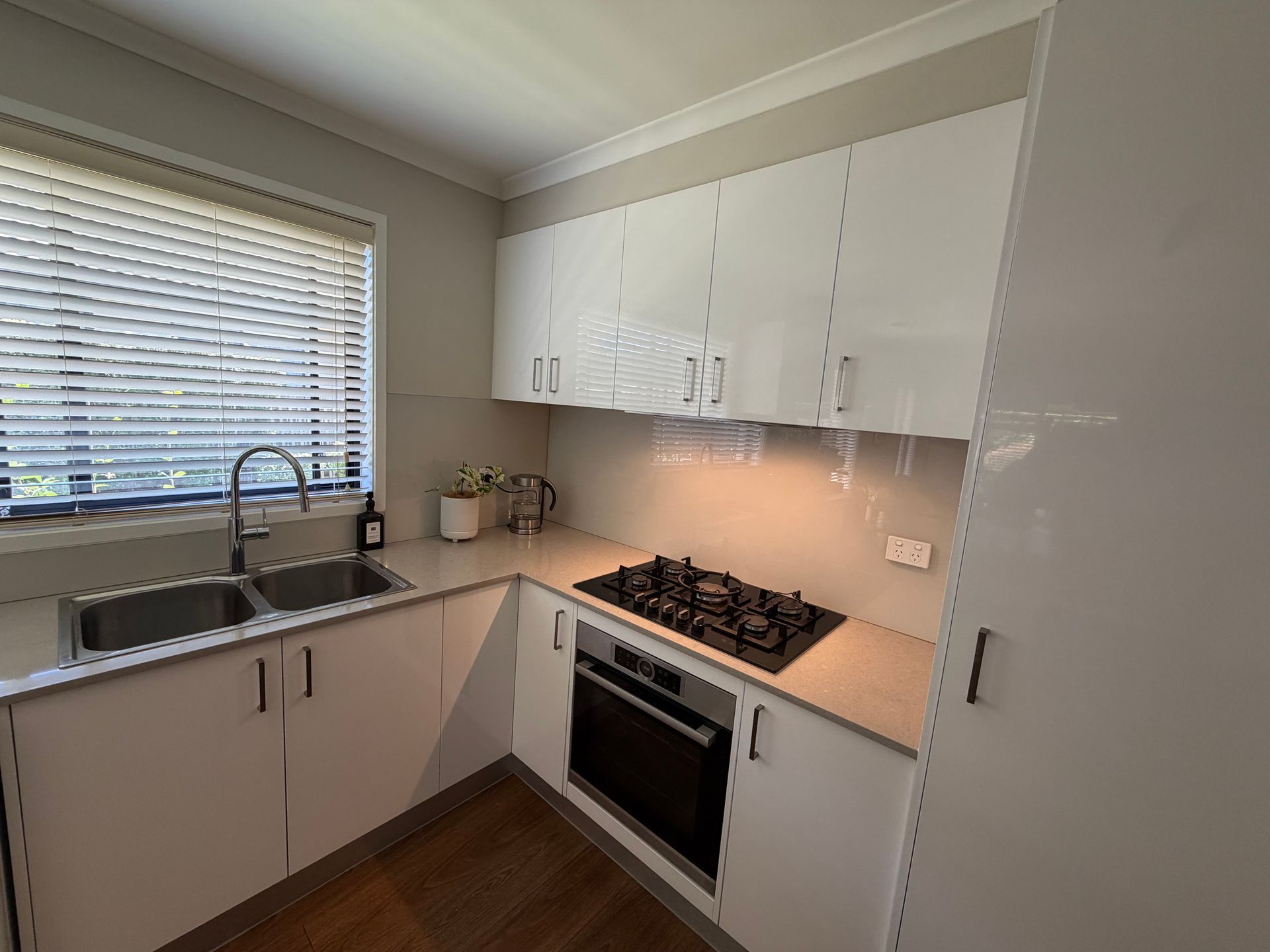 Kitchen with white cabinets, stainless steel sink, black cooktop, and built-in oven. — Straight up Building Projects in Holt, ACT