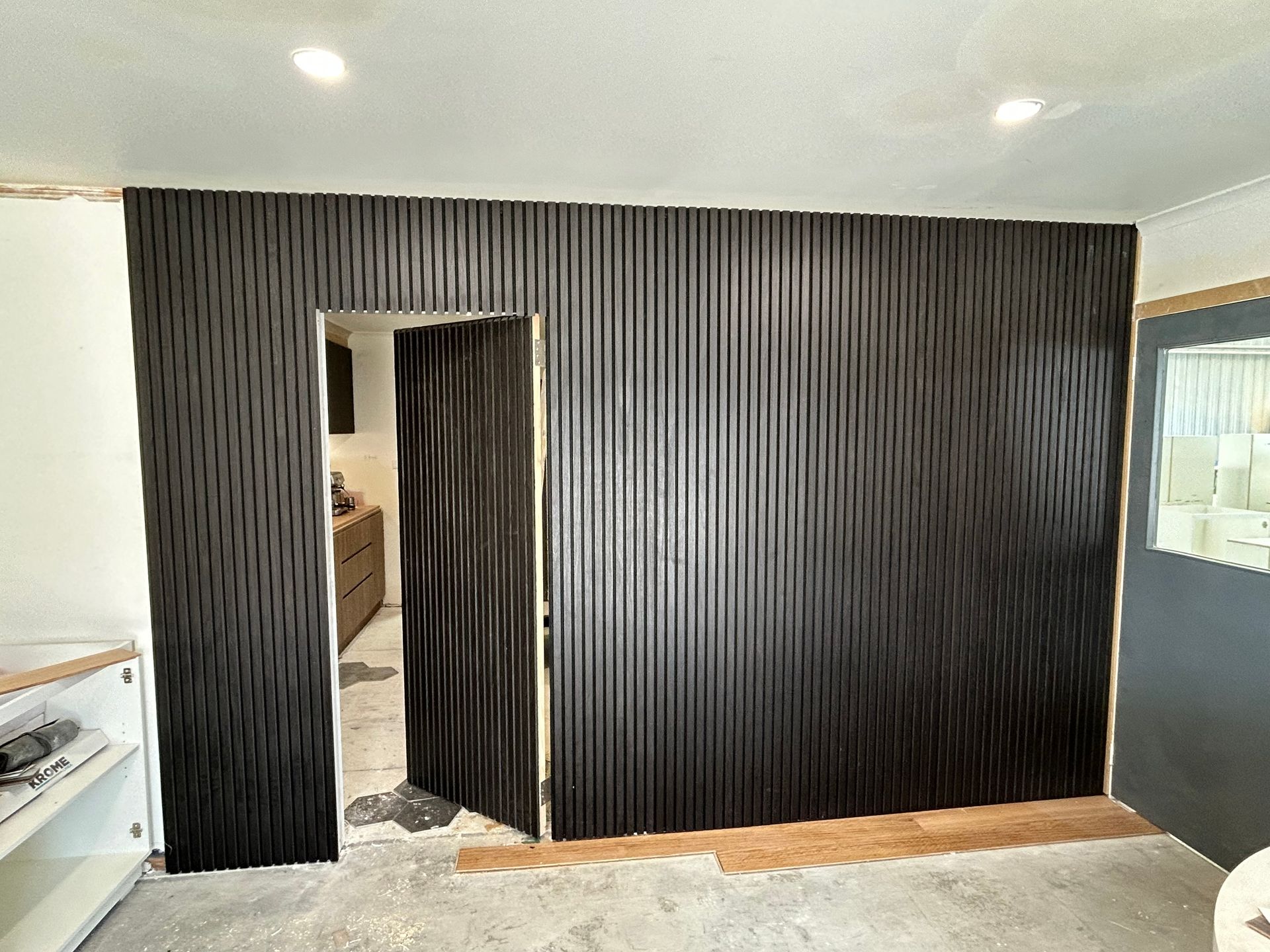 Black ribbed wall with doorway, open to a room. Construction setting. — Straight up Building Projects in Holt, ACT