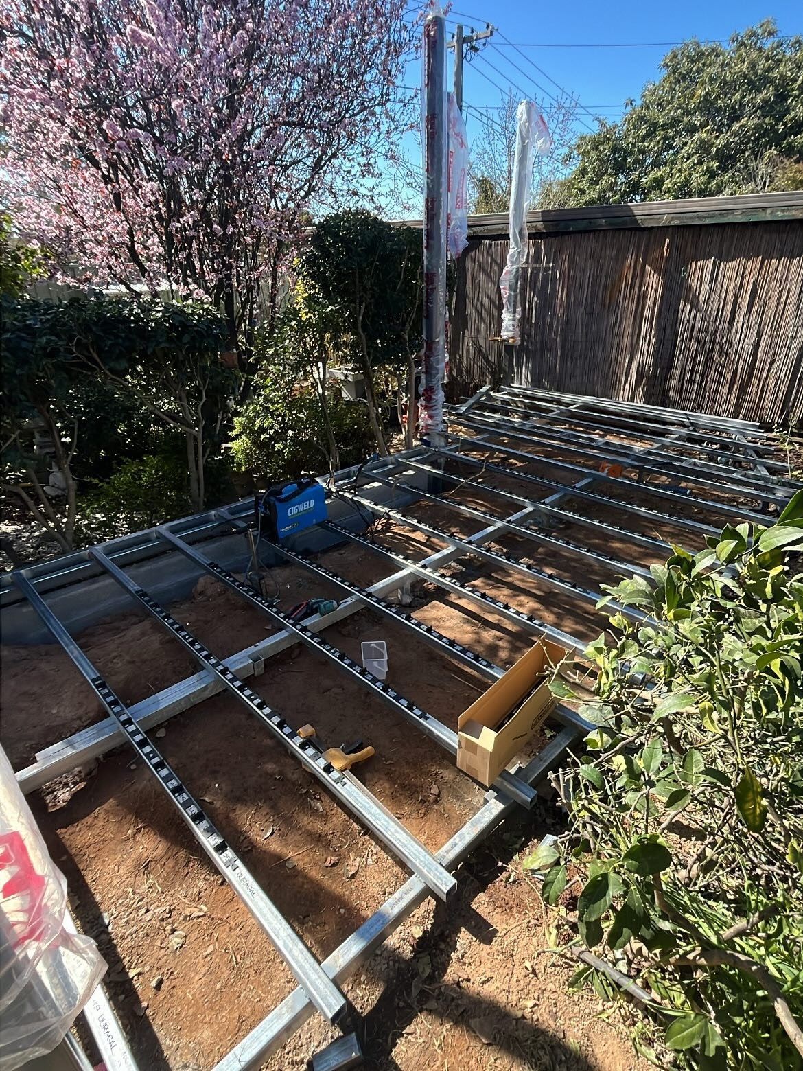 Metal frame structure laid on soil, outdoors, with tools and poles. — Straight up Building Projects in Holt, ACT