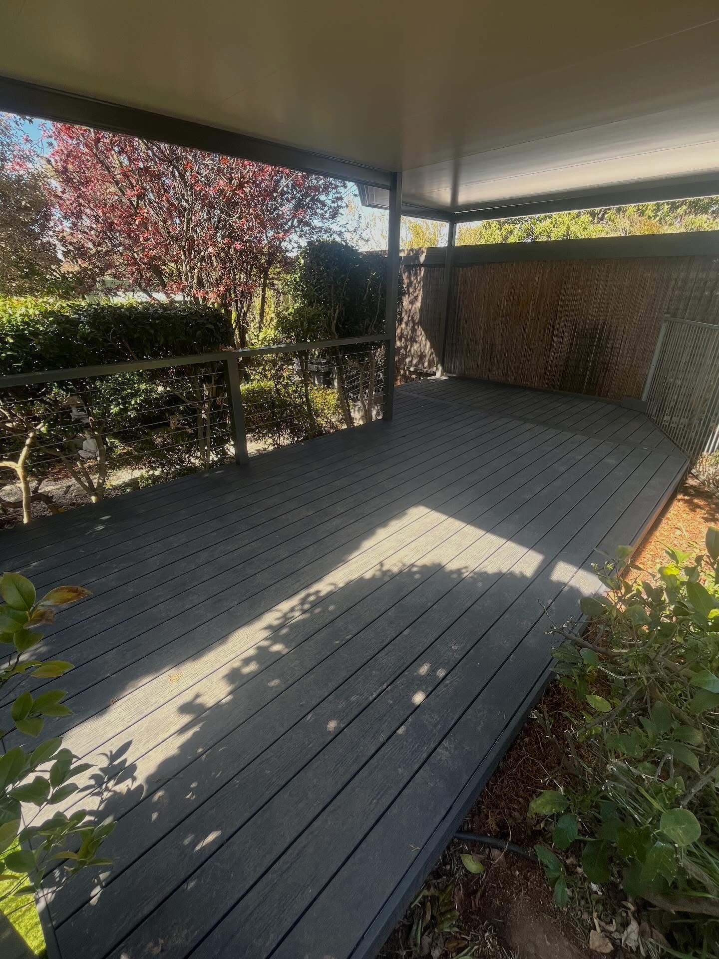 Grey wooden deck under a shaded patio with surrounding greenery. — Straight up Building Projects in Holt, ACT