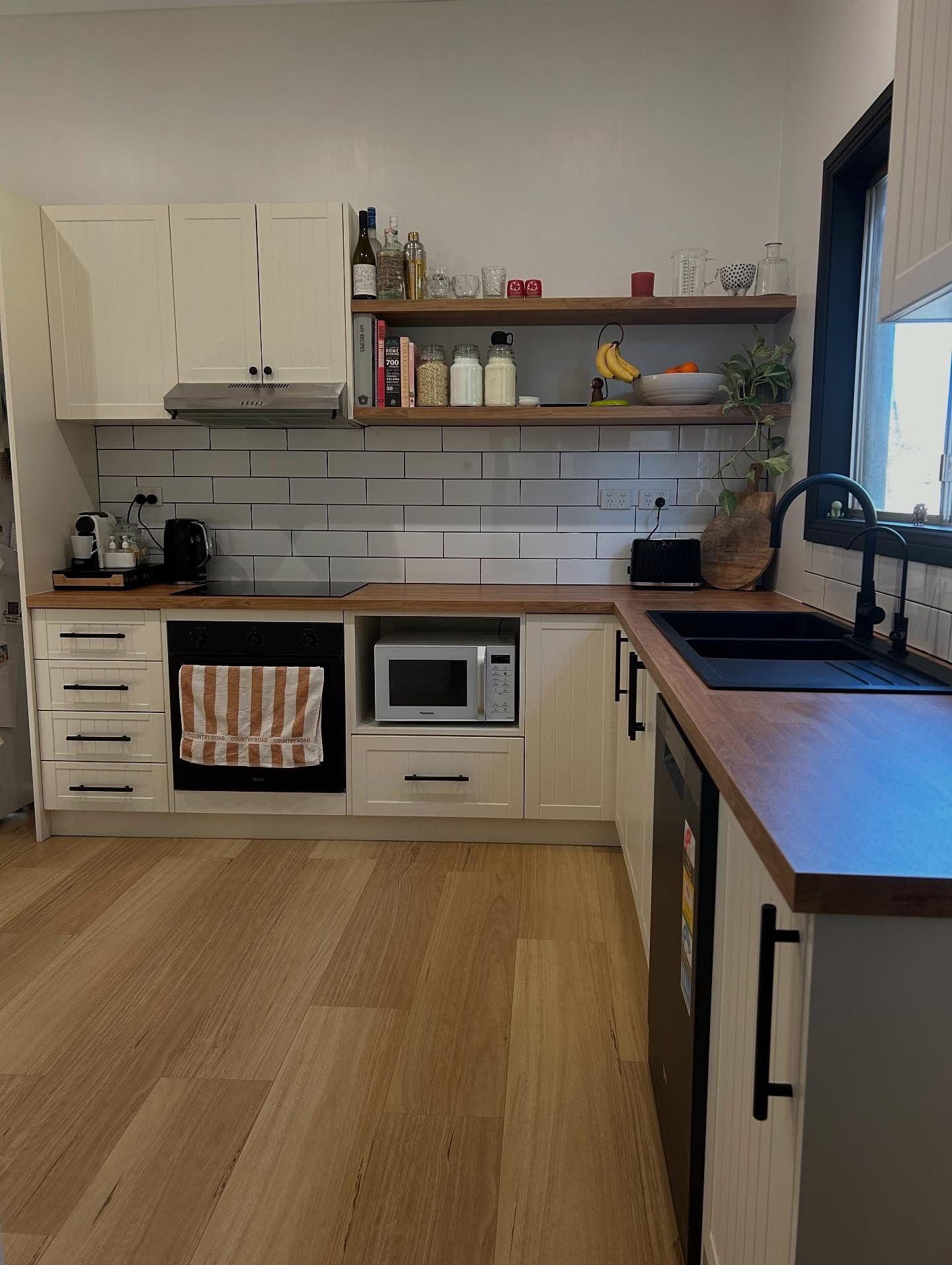 Modern kitchen with white cabinets, wooden countertops, subway tile, and black fixtures. — Straight up Building Projects in Holt, ACT