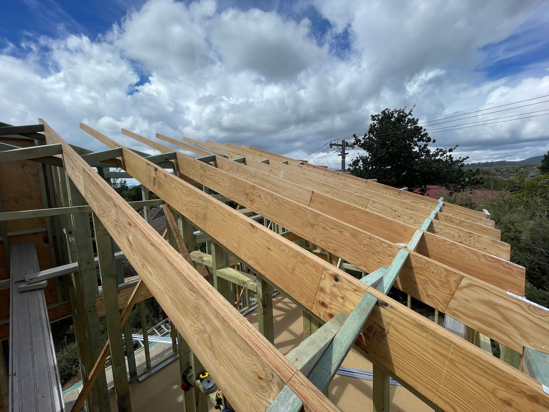 Wooden roof frame under construction, outdoors with cloudy sky. — Straight up Building Projects in Holt, ACT