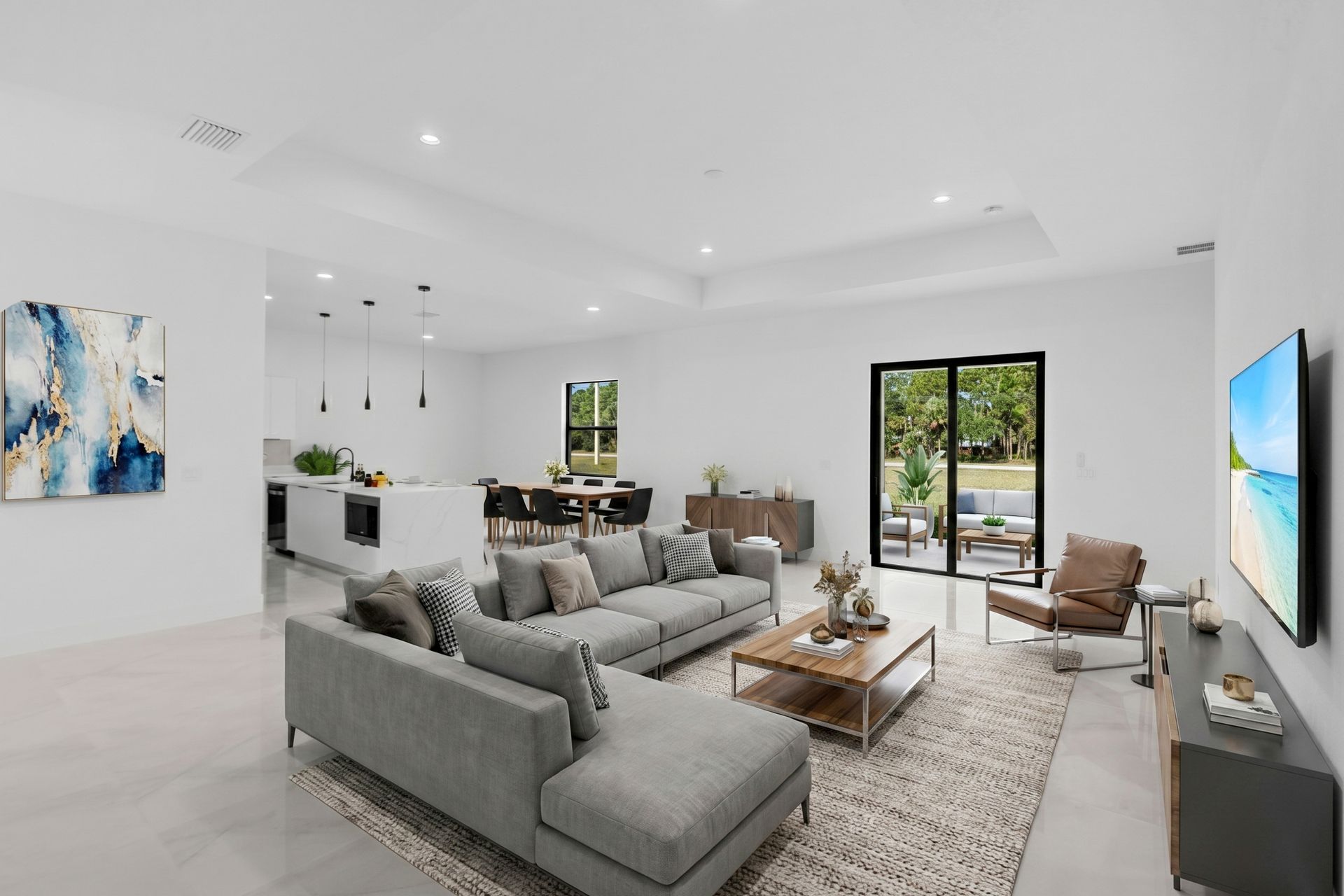 Modern open-concept living space with a sectional sofa, kitchen island, and dining area, all in a bright, white color scheme.