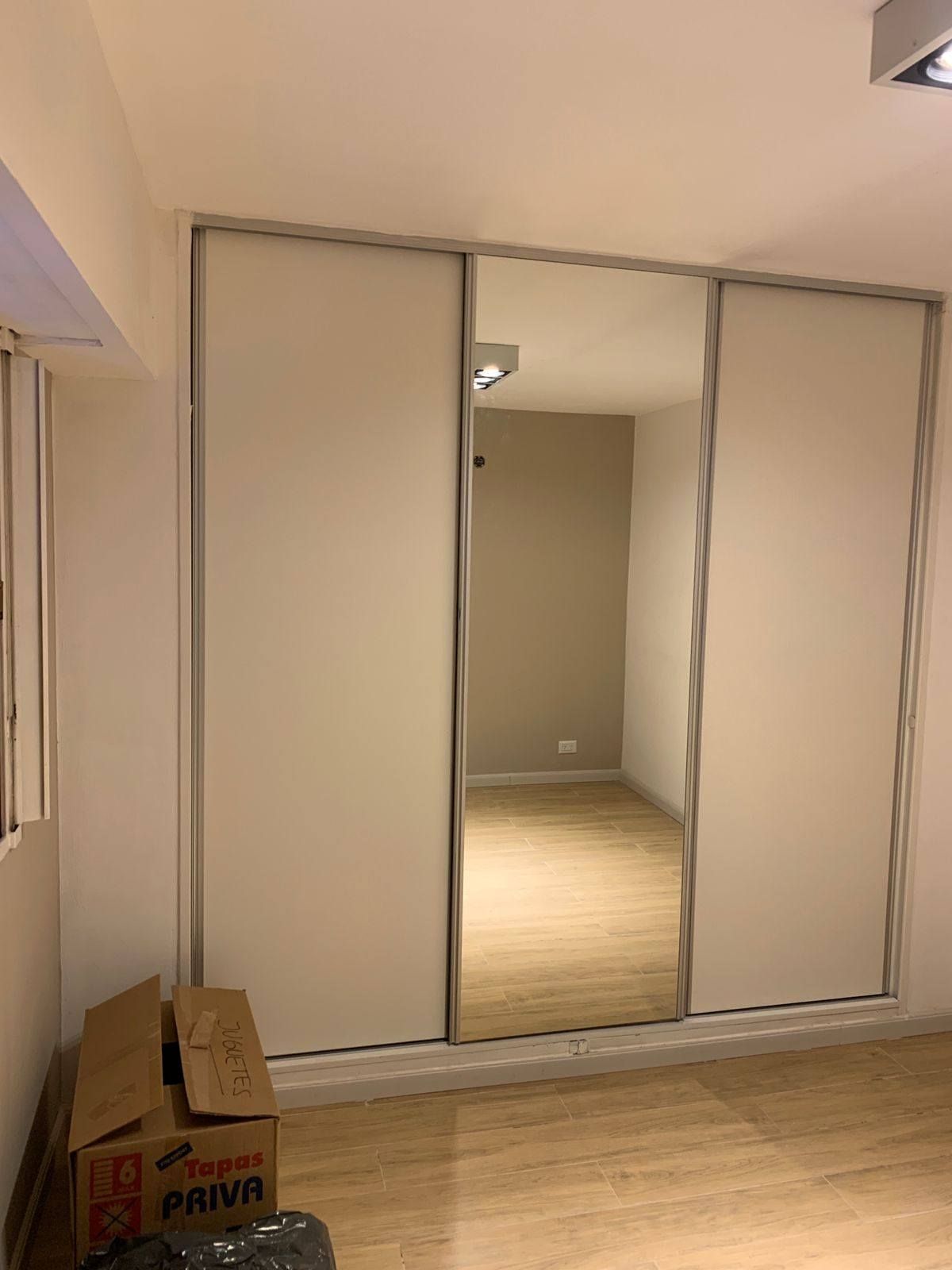 Armario con puertas corredizas y panel central de espejo