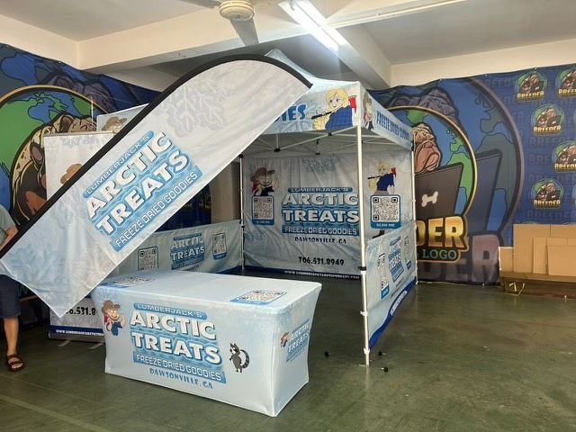 Arctic Treats branded pop-up booth with white and blue canopy and table in a colorful indoor venue