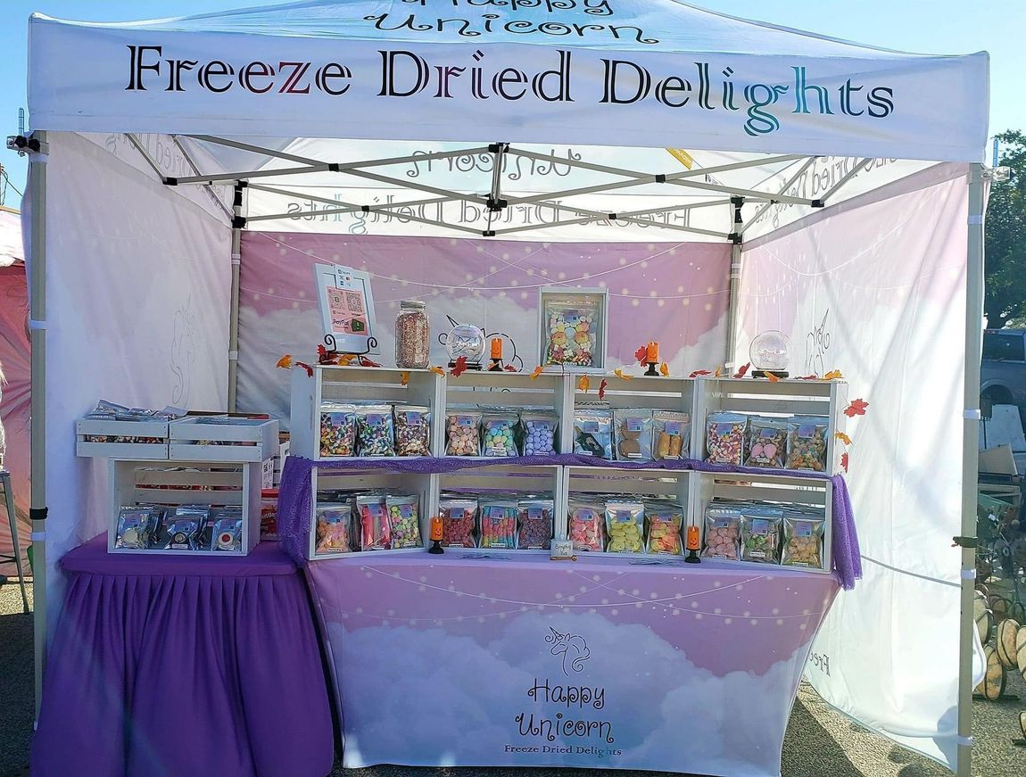 Freeze-dried treats stall with pastel shelves and a purple tablecloth inside a white canopy.