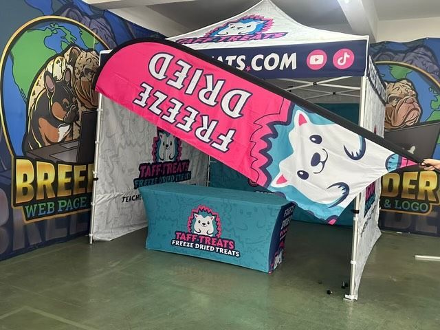 Event booth with a blue table and pink “FREEZE FRIED” sign under a colorful canopy
