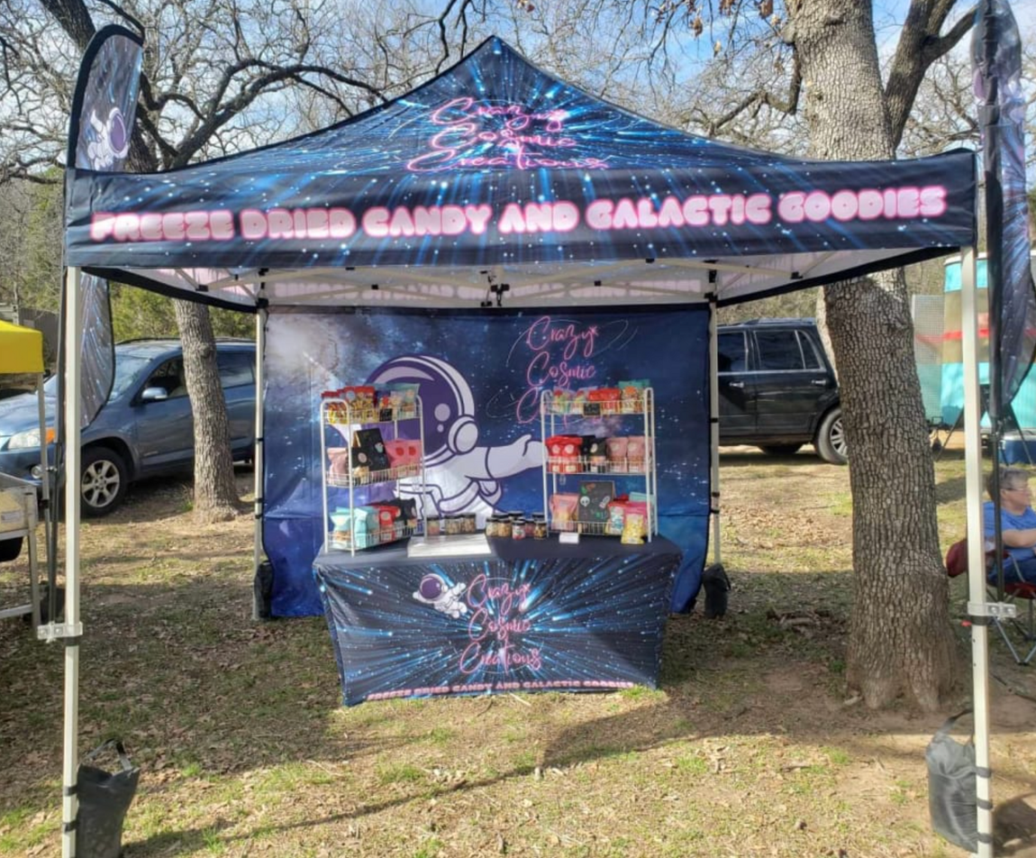 Candy vendor tent with colorful space-themed display and pink signage outdoors