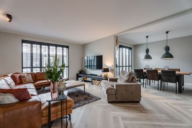 Een woonkamer met een tafel, stoelen en een schilderij aan de muur.