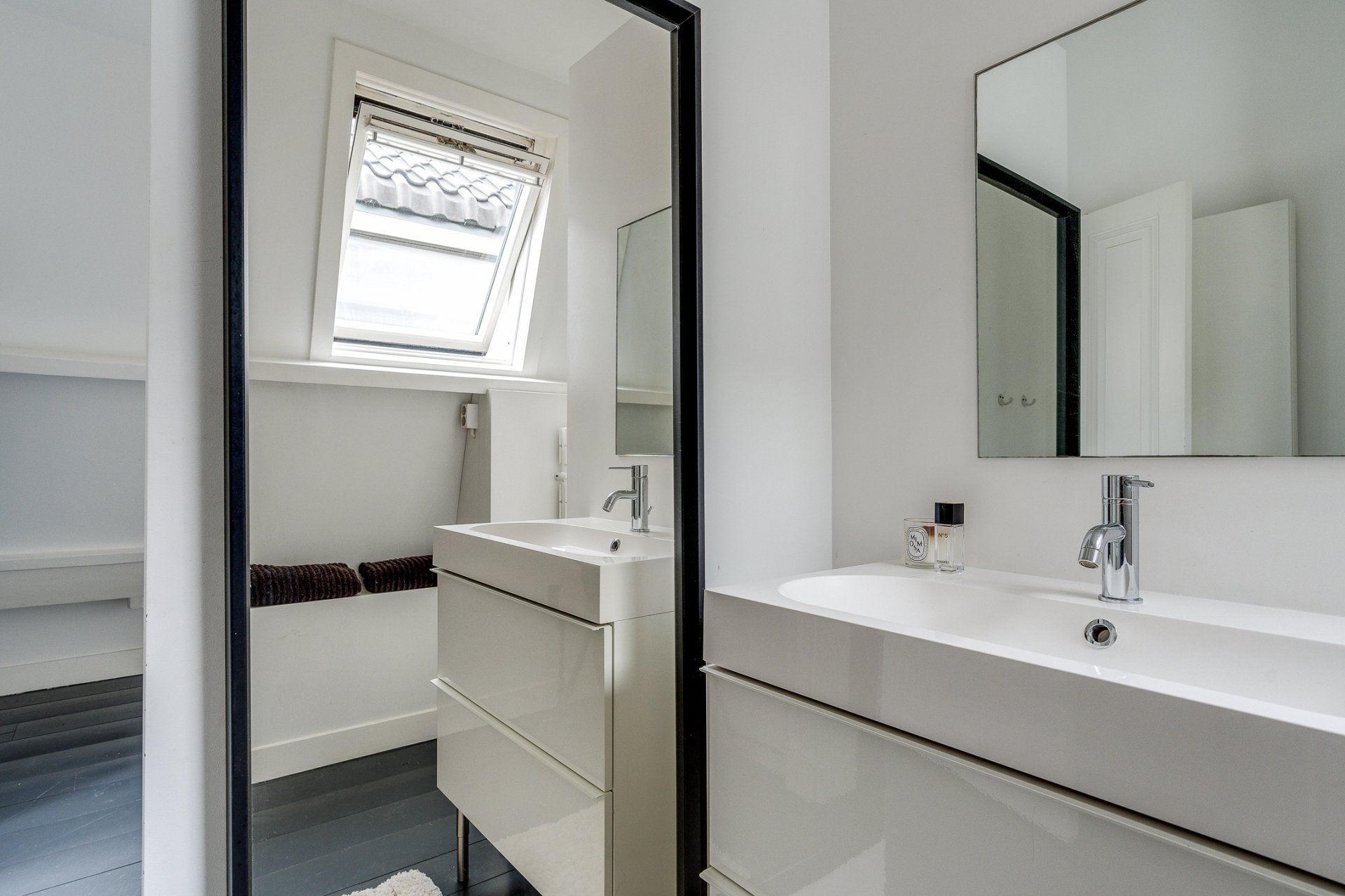 Een badkamer met twee wastafels, een spiegel en een raam.