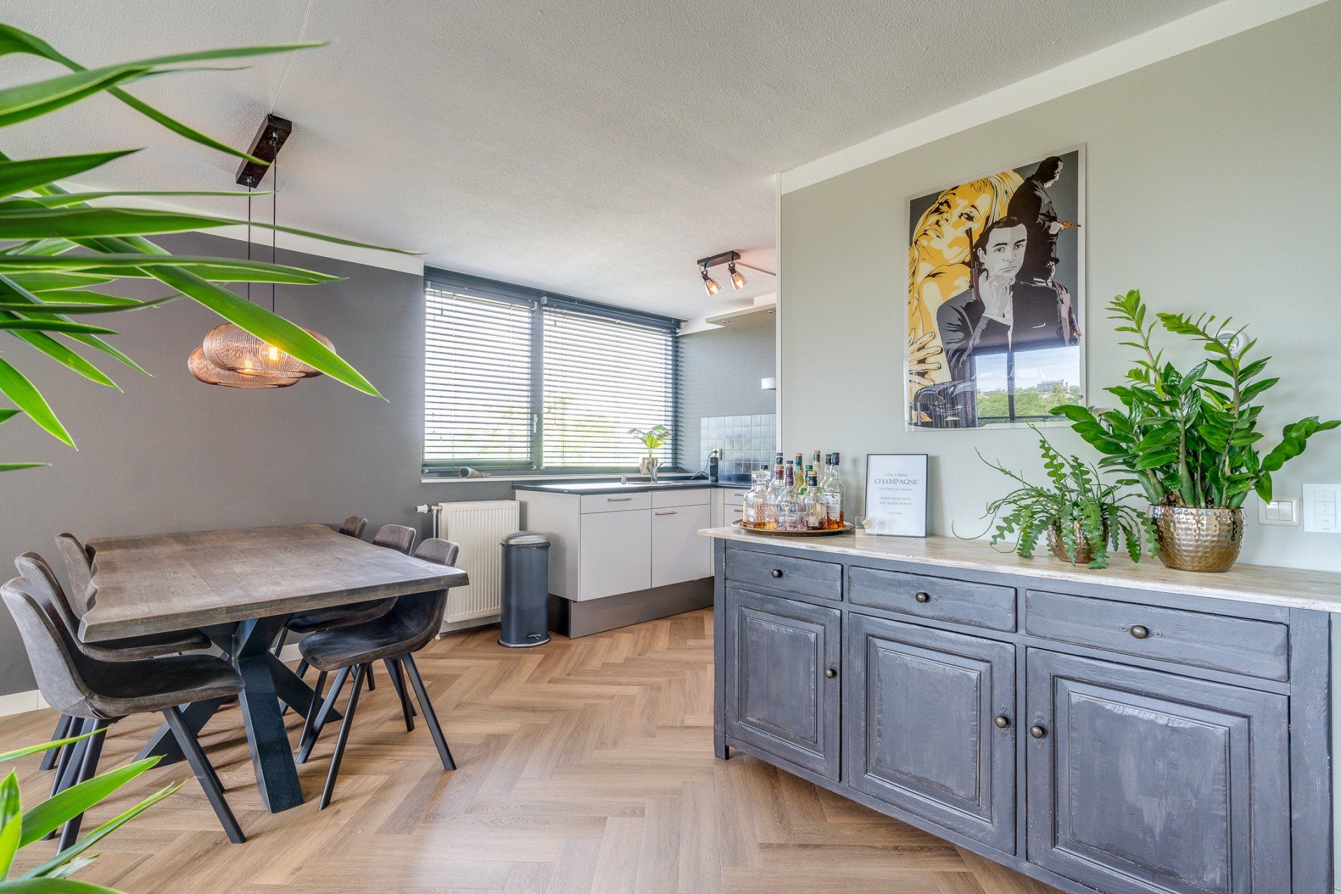 Een woonkamer met een tafel, stoelen en een schilderij aan de muur.