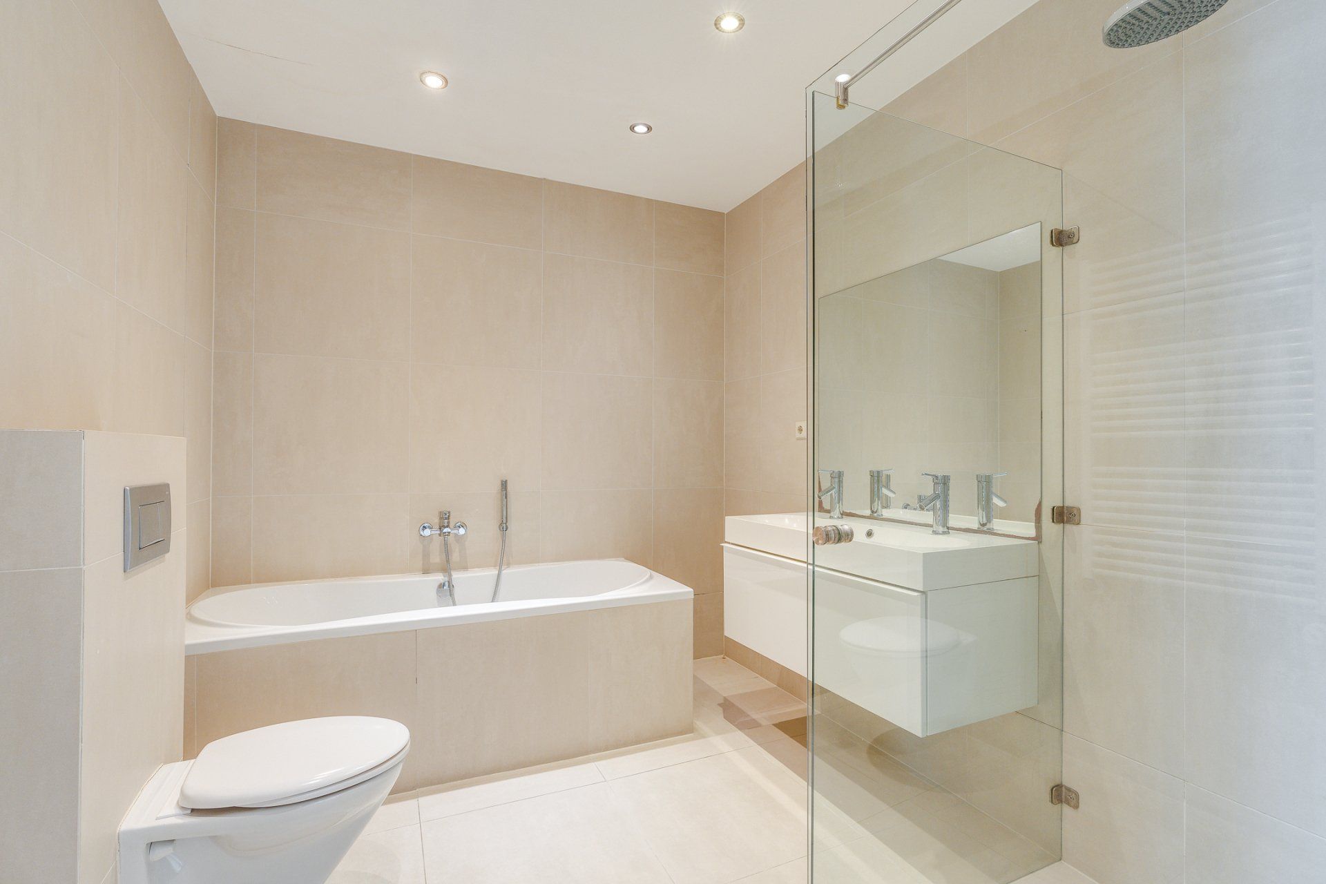 Een badkamer met ligbad, toilet, wastafel en douche.