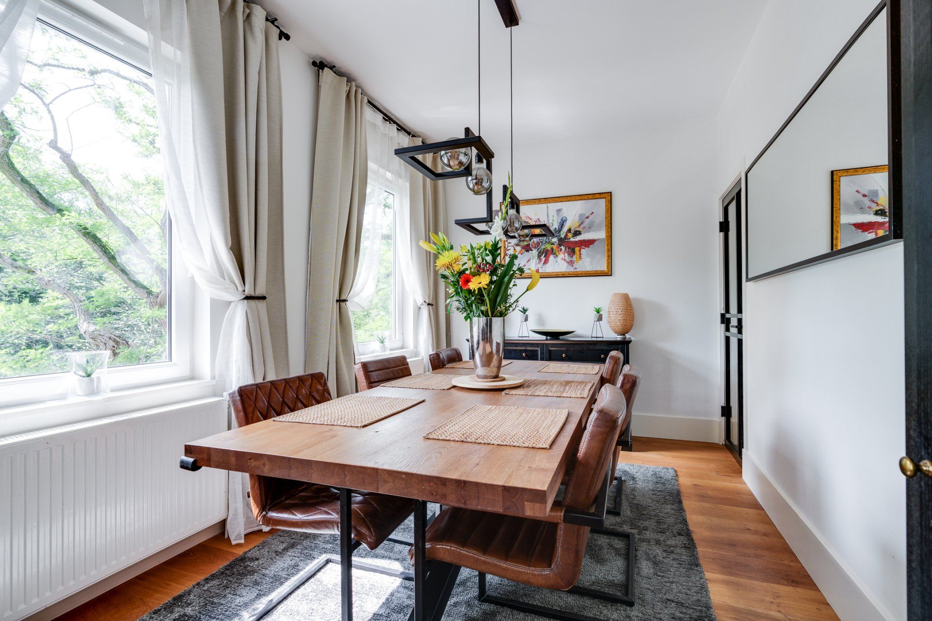 Een eetkamer met een lange houten tafel en stoelen.