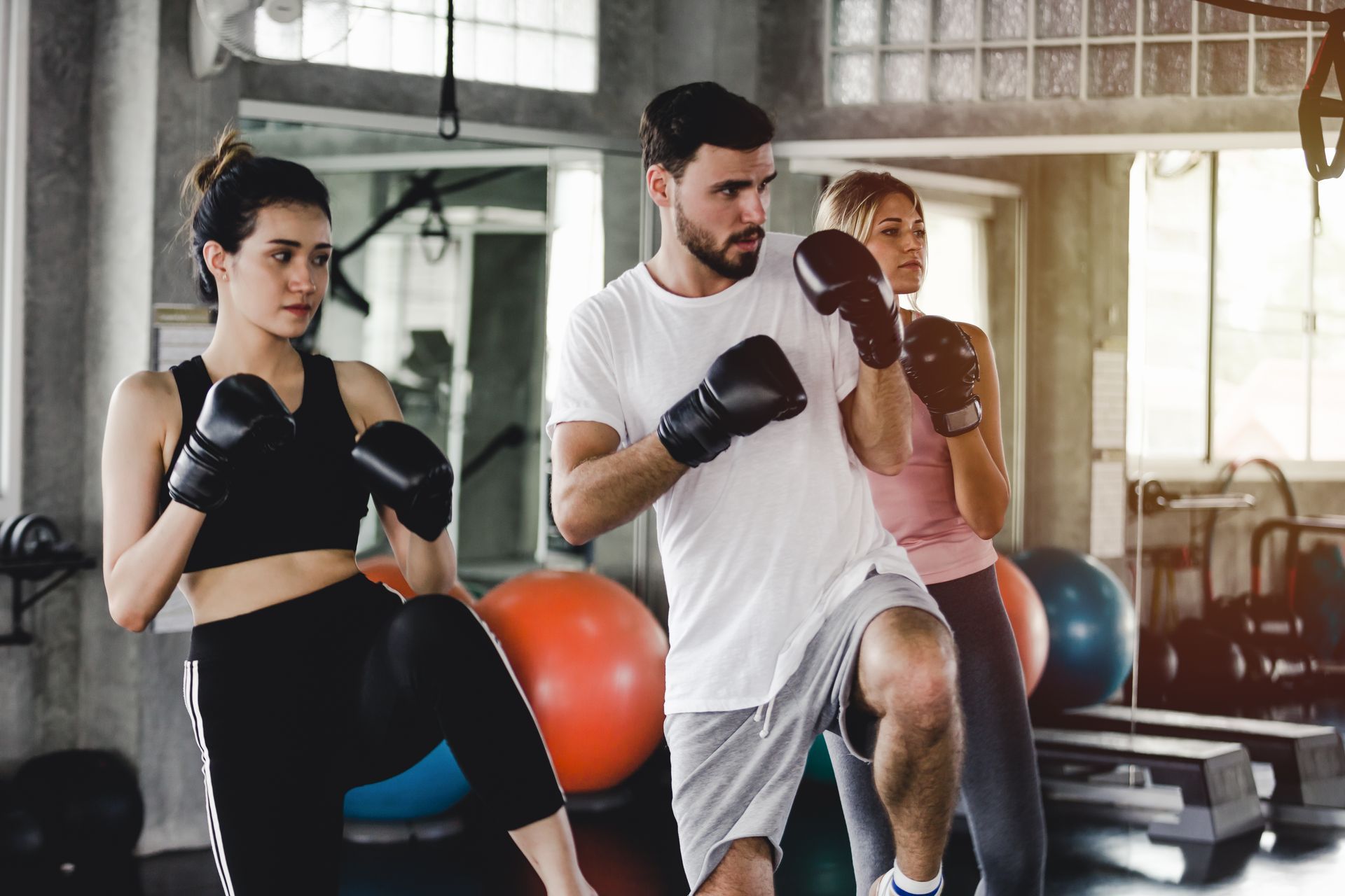 Un uomo e due donne stanno praticando boxe in una palestra.
