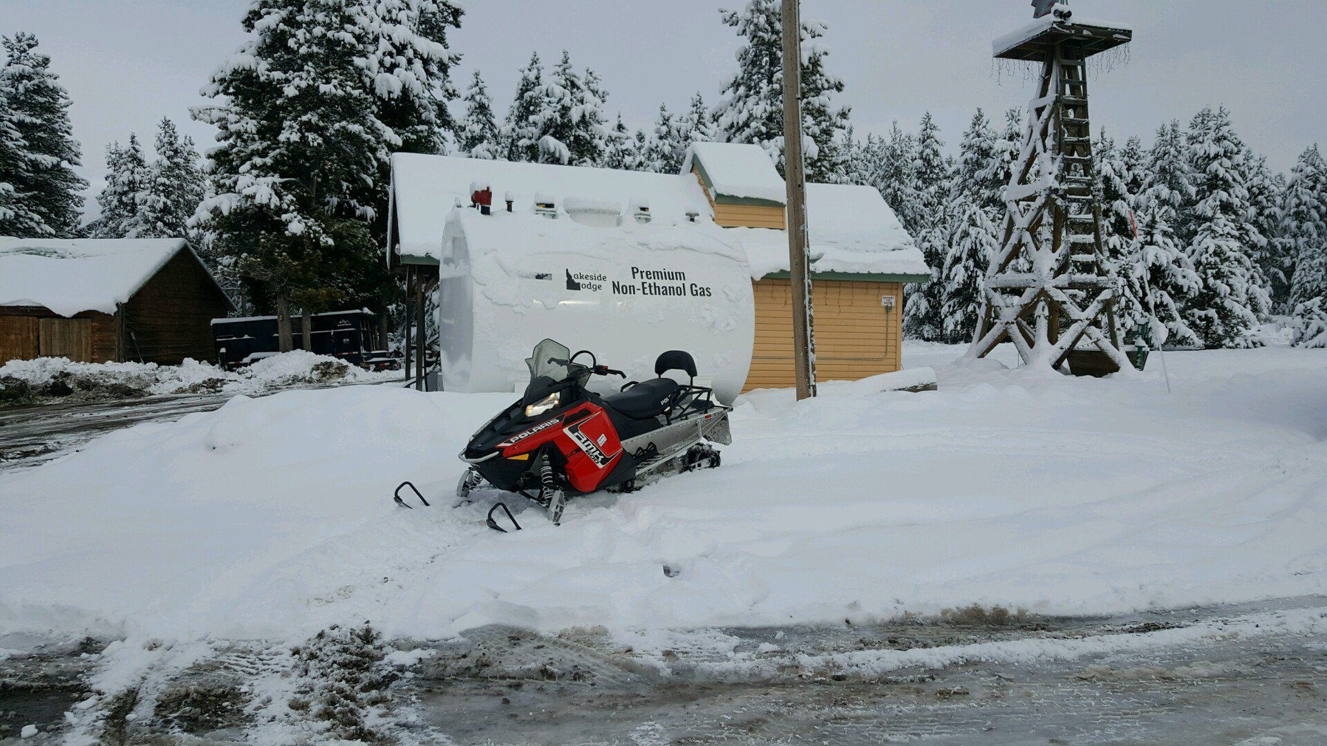 Red snowmobile parked outside a cabin