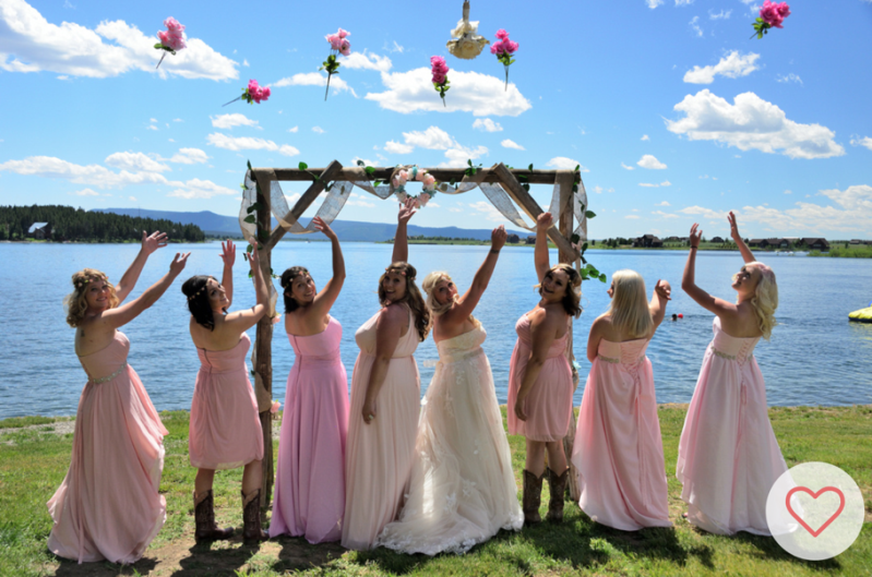 Bride and bridesmaids reaching for the bouquet of flowers