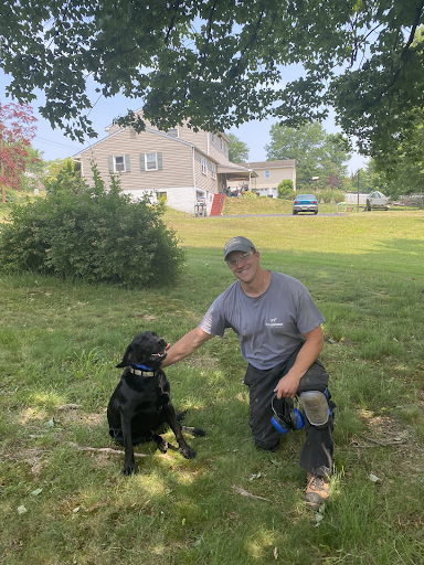 dan with black lab sitting on grass