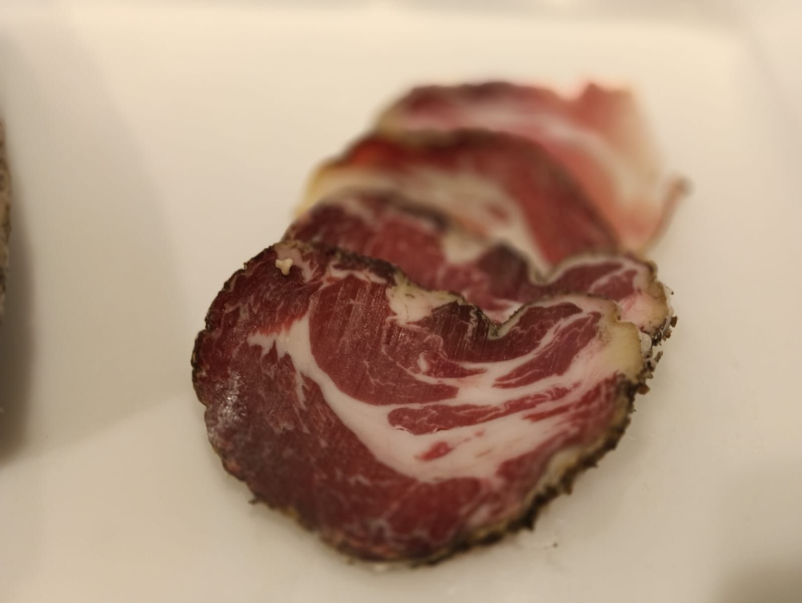 Prodotti a base di carne esposti in un banco refrigerato, tra cui salsicce confezionate e carne macinata.