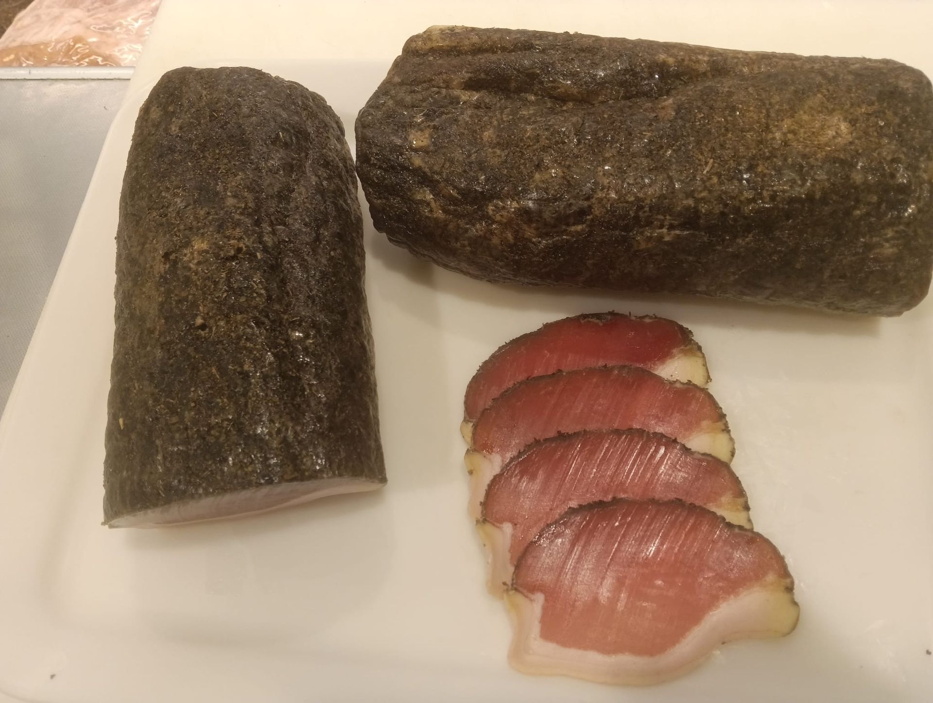 Prodotti a base di carne esposti in un banco refrigerato, tra cui salsicce confezionate e carne macinata.