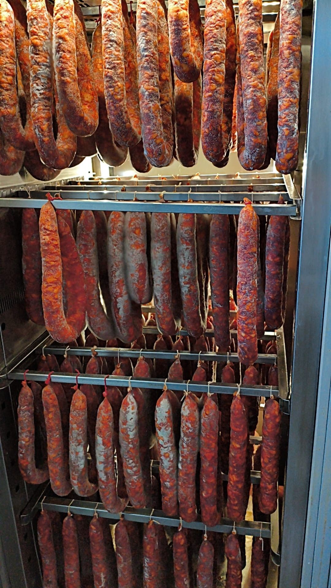 Prodotti a base di carne esposti in un banco refrigerato, tra cui salsicce confezionate e carne macinata.