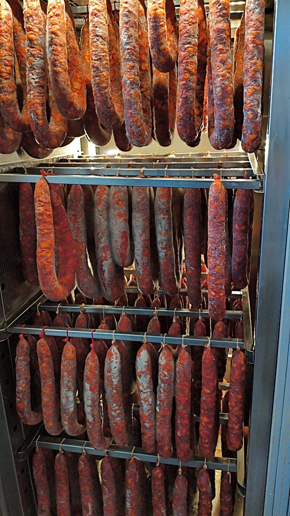 Prodotti a base di carne esposti in un banco refrigerato, tra cui salsicce confezionate e carne macinata.