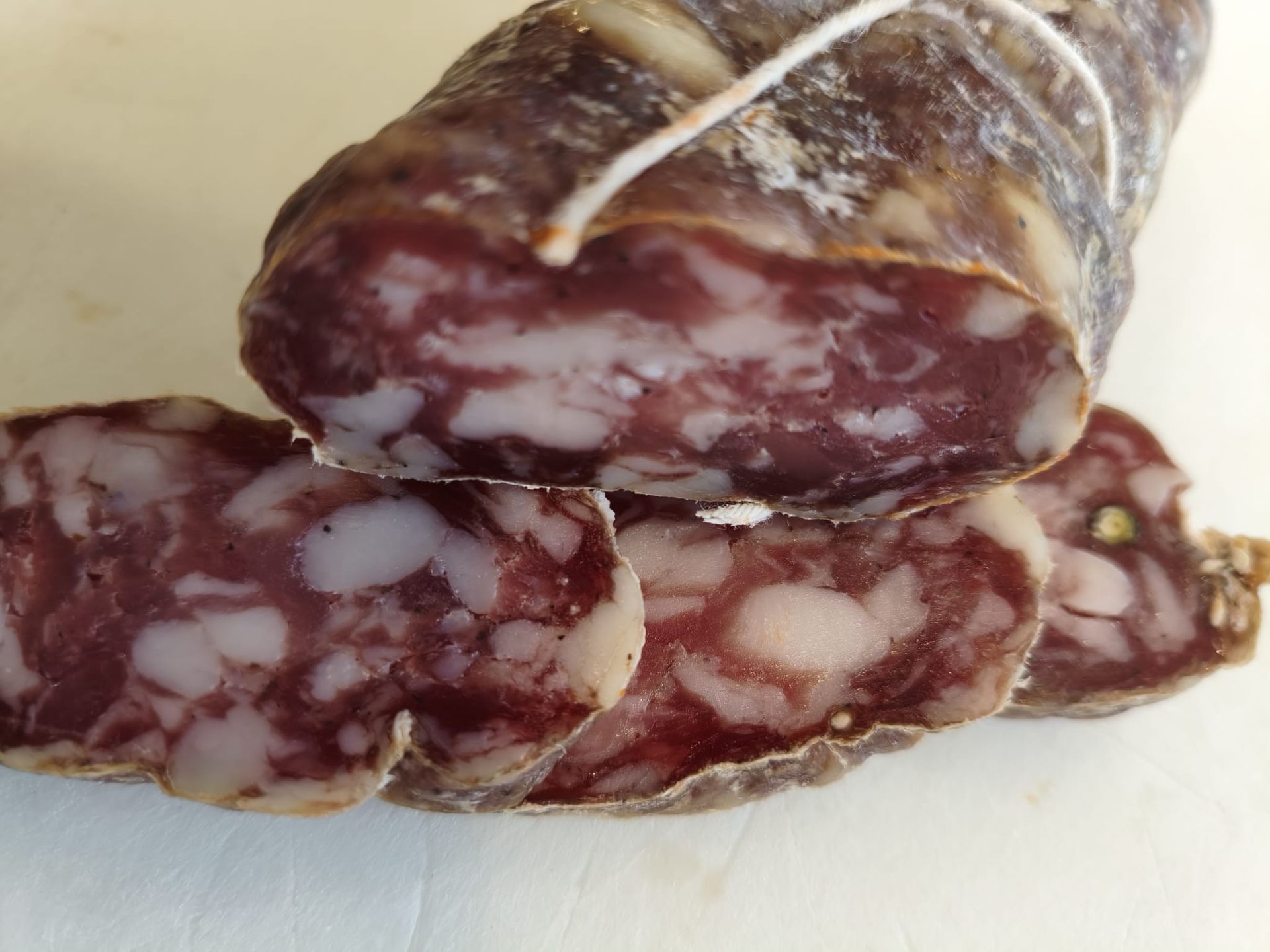 Prodotti a base di carne esposti in un banco refrigerato, tra cui salsicce confezionate e carne macinata.