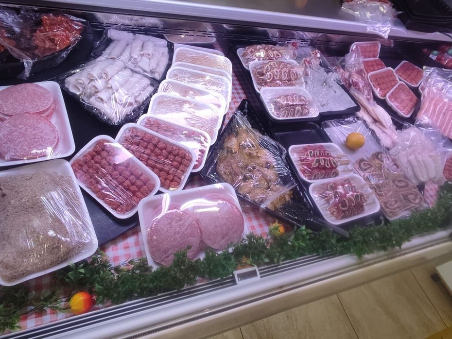 Prodotti a base di carne esposti in un banco refrigerato, tra cui salsicce confezionate e carne macinata.