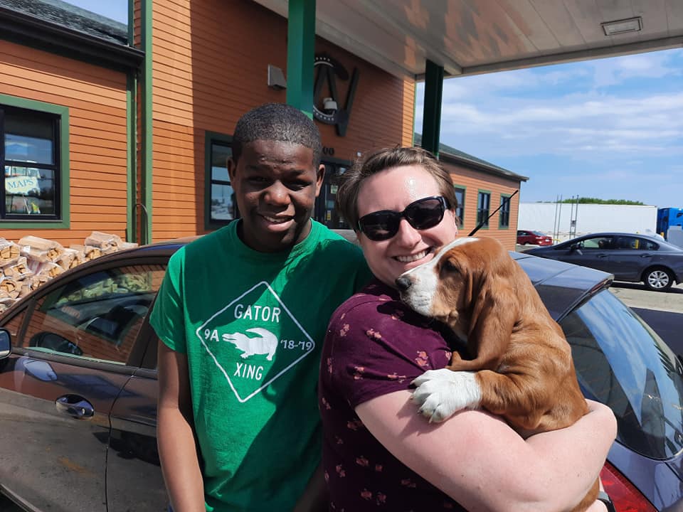 A man in a green gator shirt is holding a puppy