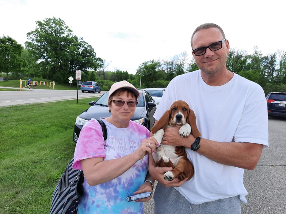 A man and a woman are holding a brown and white dog.
